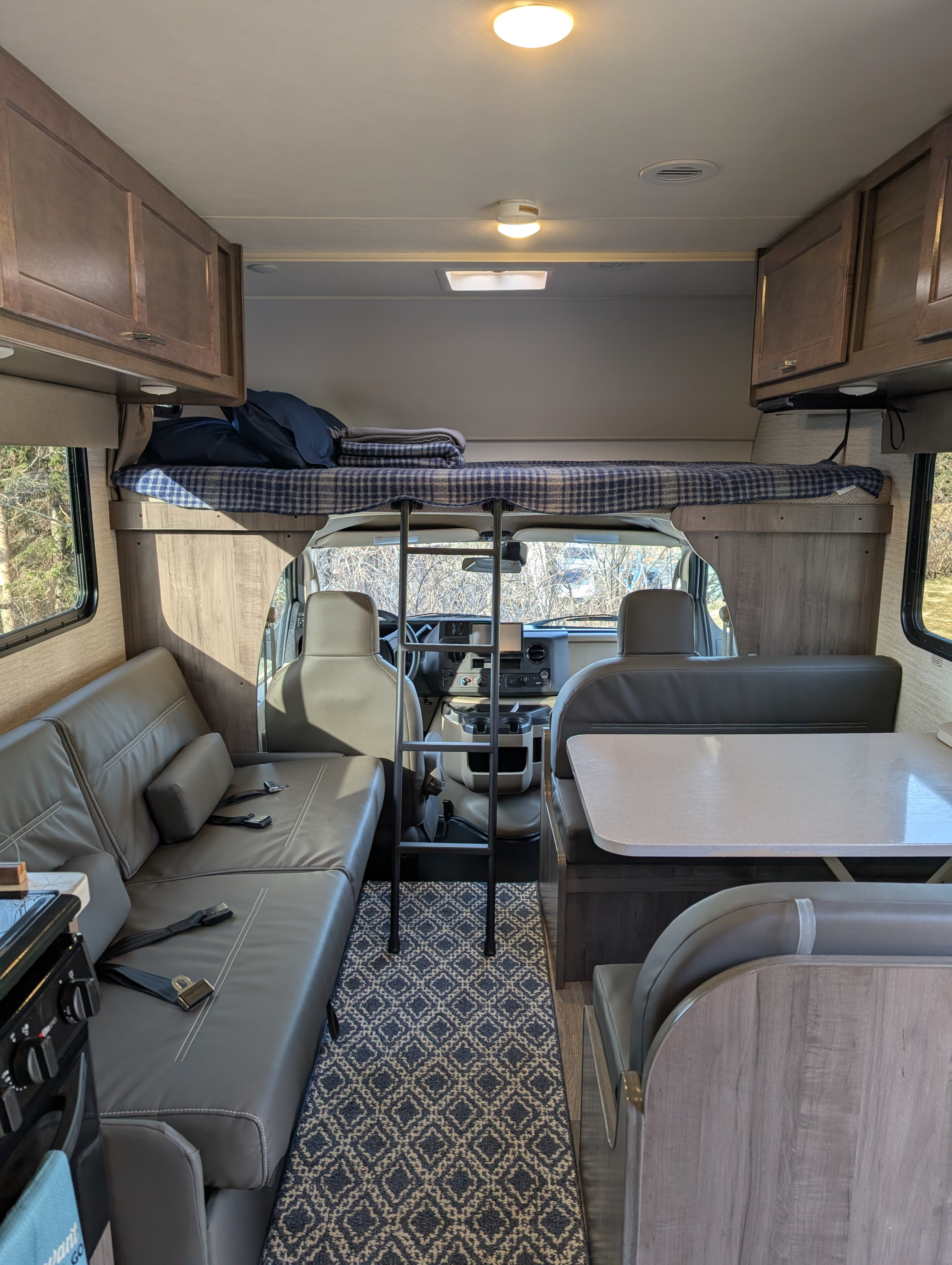 Spacious RV rental interior with overhead bed, dinette, and kitchen, ideal for a comfortable road trip.. Winnebago Minnie Winnie 2023