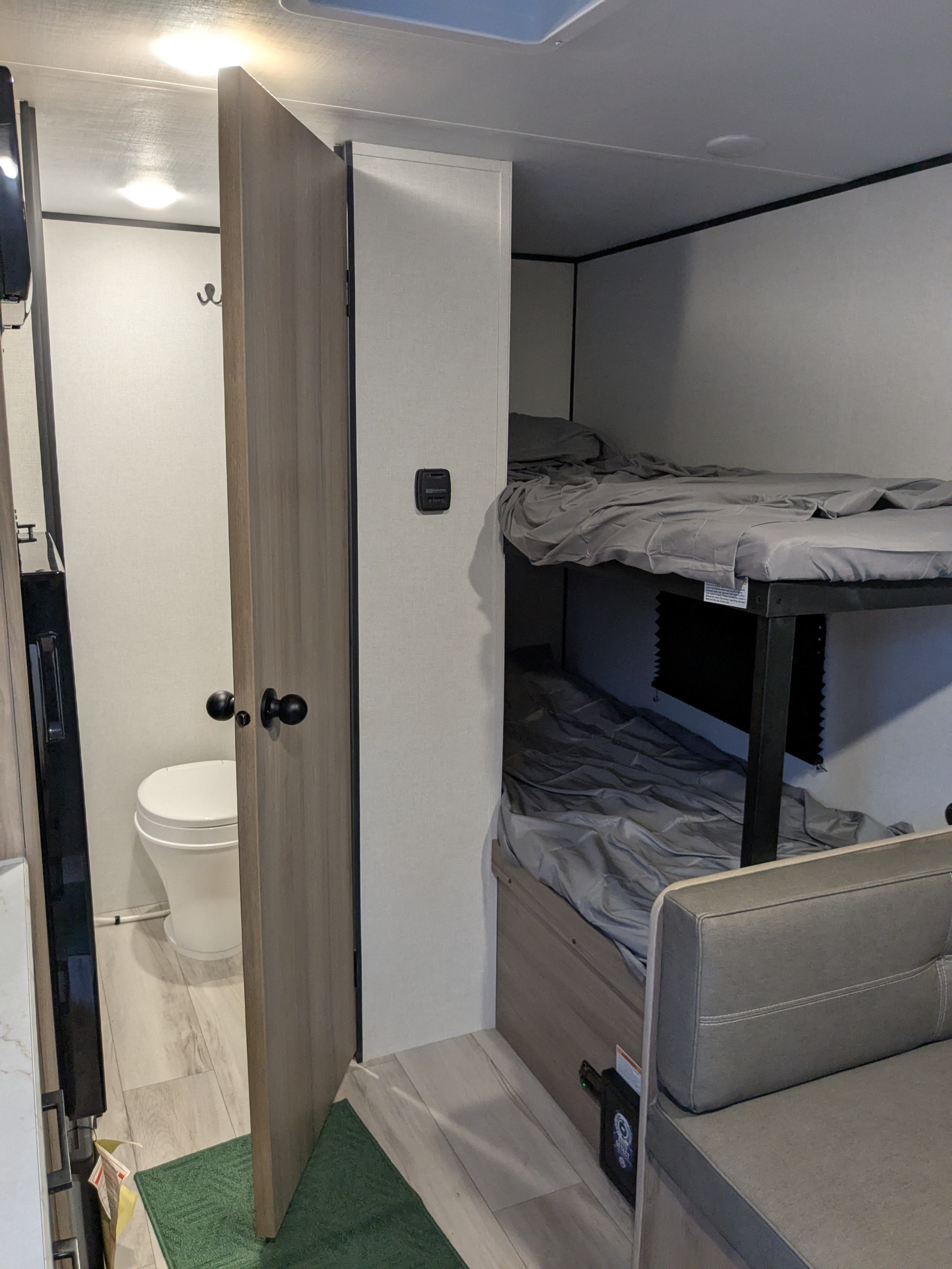 RV rental interior: compact layout with private bathroom, bunk beds, and lounge area. Perfect for family travel.. Keystone Coleman 2025