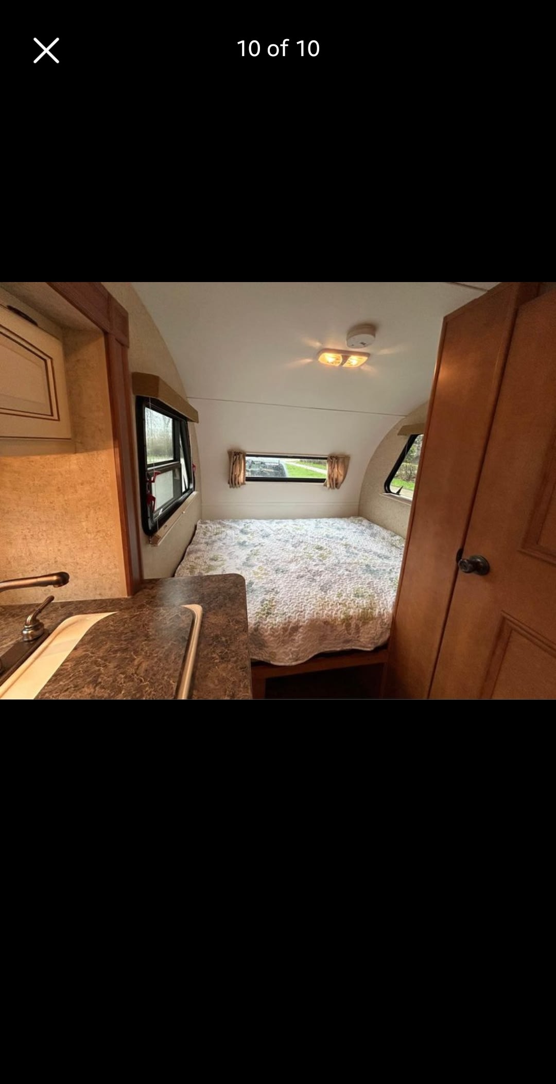 RV rental interior: cozy bedroom with floral bed, compact kitchenette, & bright windows.. Heartland RVs MPG 2011