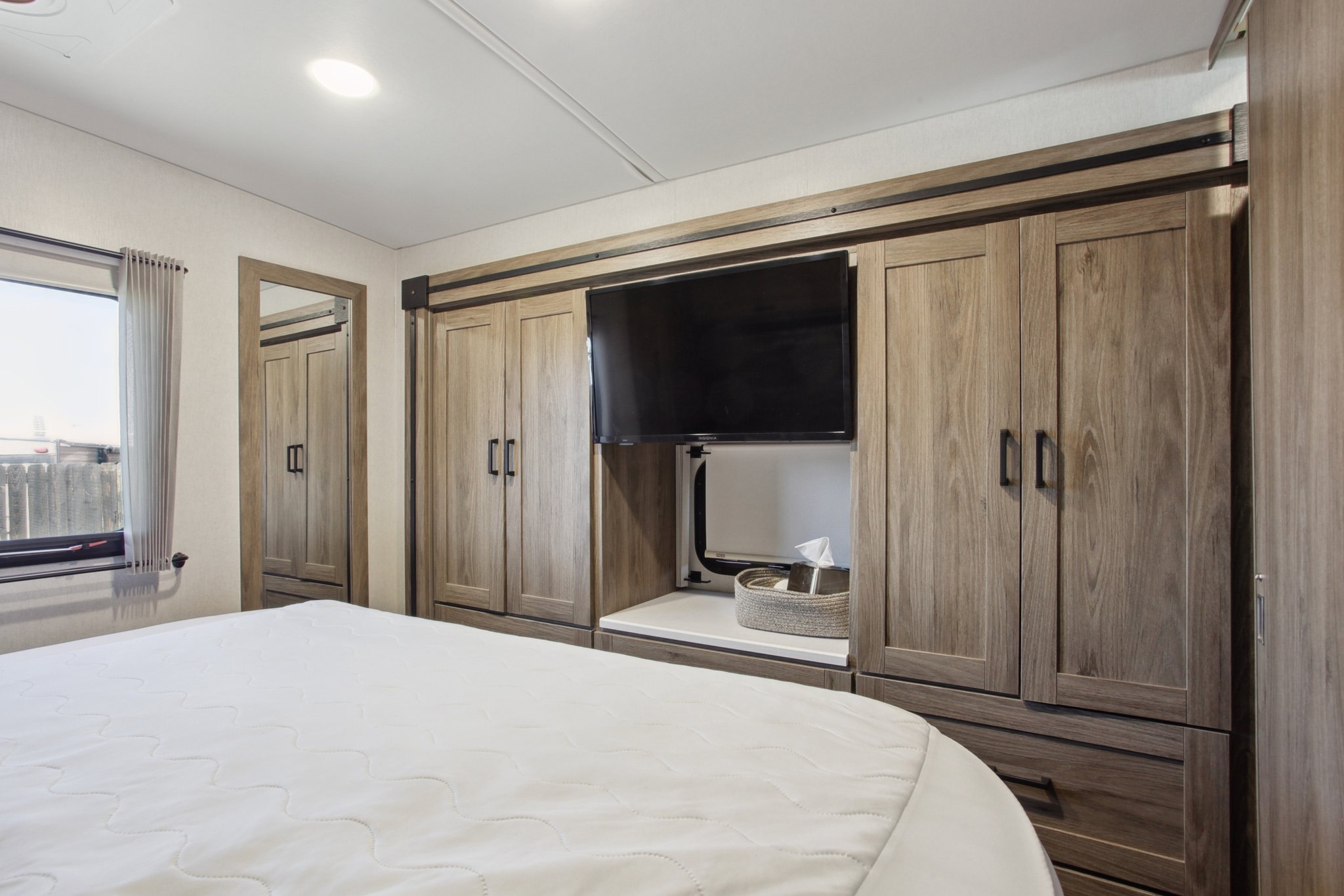Modern RV rental bedroom boasts a large bed, integrated storage cabinetry, and TV for a cozy stay.. Winnebago Vista 2023