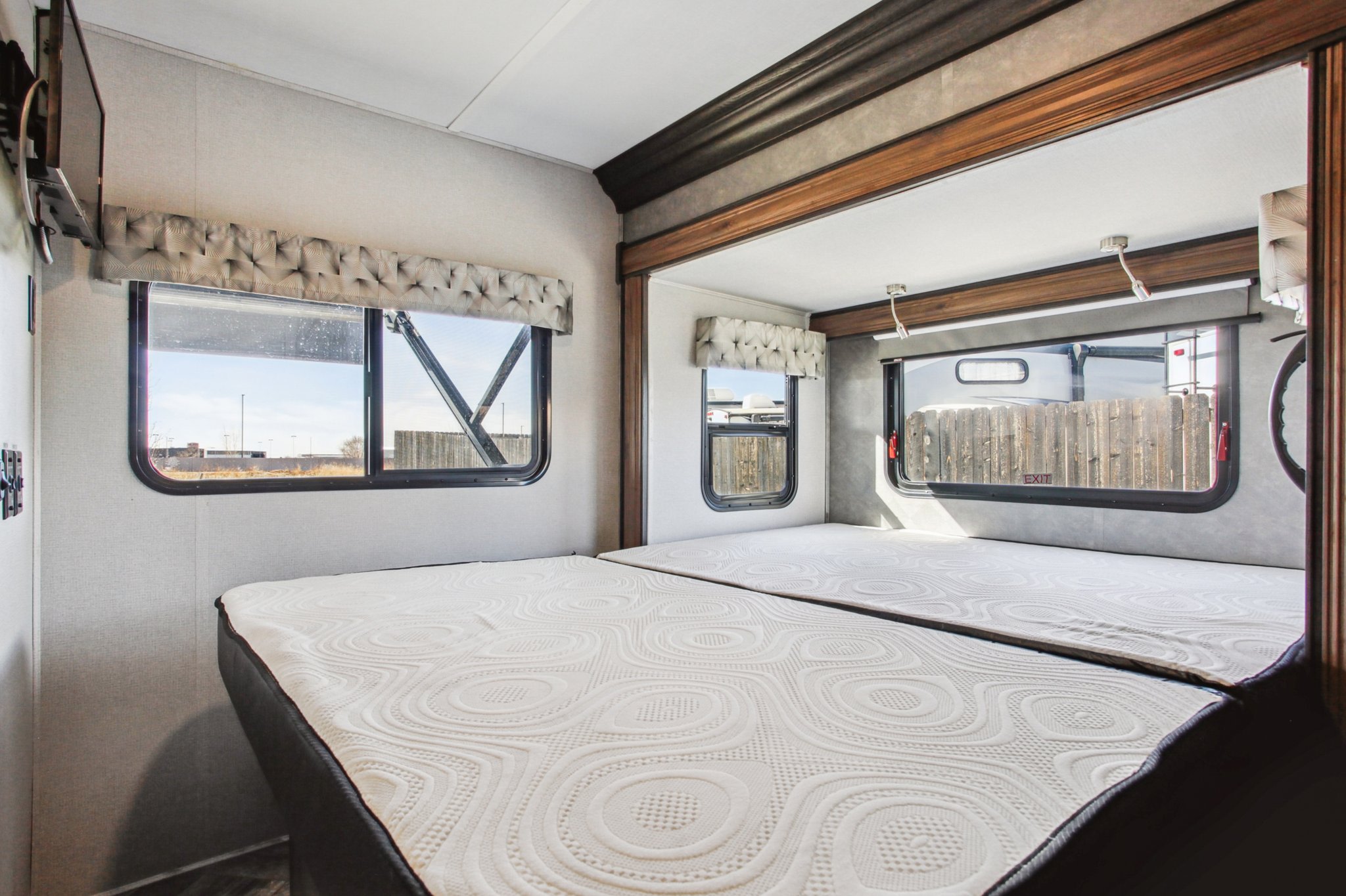This RV rental features a comfortable sleeping area with two beds, large windows, and a mounted TV, perfect for mobile living.. Forest River Sunseeker 2021