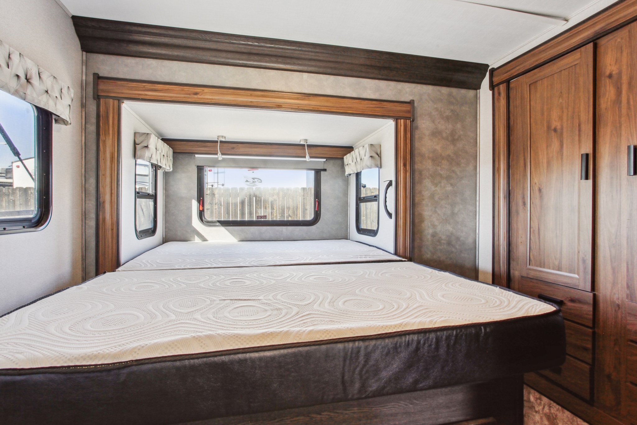 Spacious RV bedroom featuring two comfortable mattresses, large windows, and built-in storage, perfect for your RV rental.. Forest River Sunseeker 2021