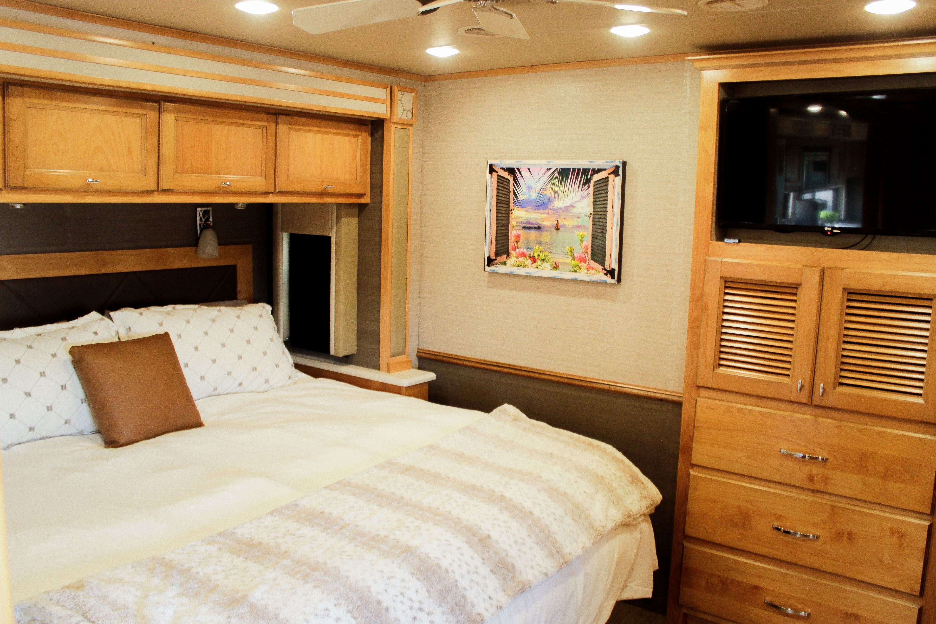 Cozy RV rental bedroom with a comfy bed, overhead storage, TV, and decorative art. Perfect for travel accommodations.. Allegro Allegro Open Road 2021