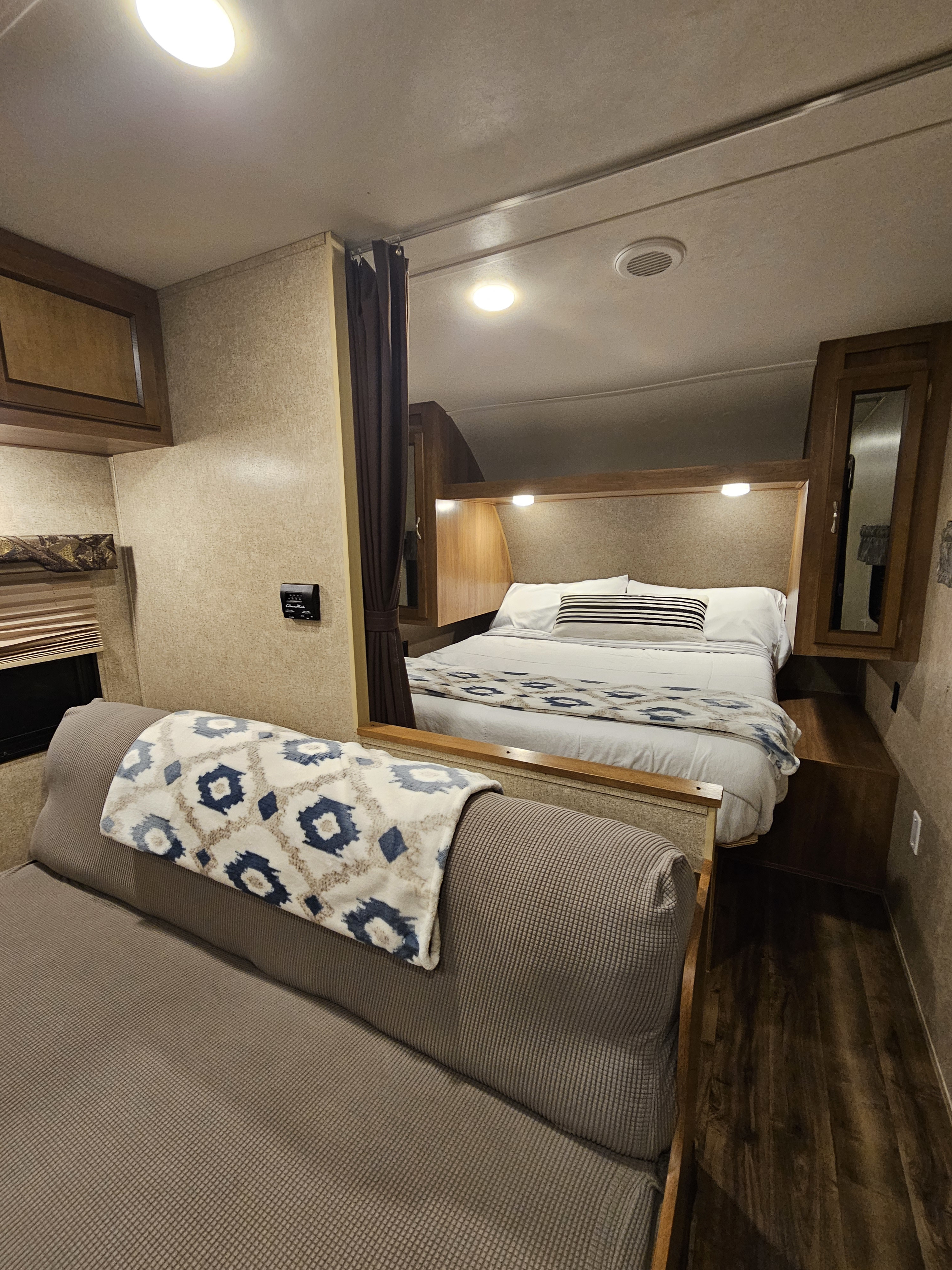 Cozy RV rental interior featuring a comfortable bedroom with a striped pillow and a seating area with a patterned blanket.. Forest River Catalina 2017