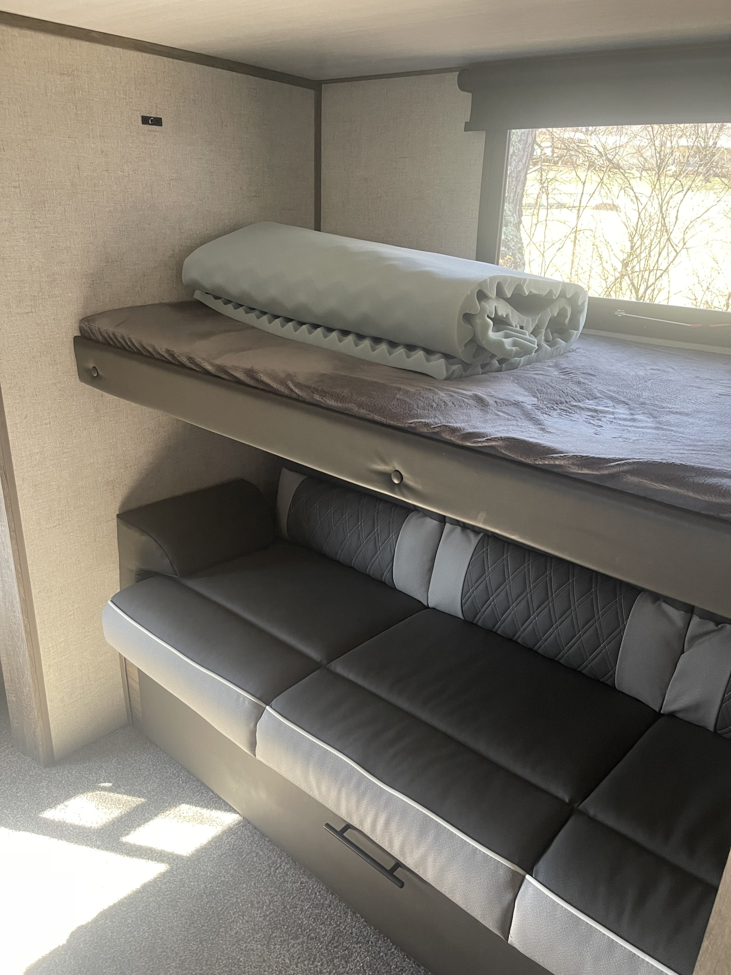 Inside an RV rental: a comfortable bunk bed above a versatile sofa, designed for compact living on the go.. Forest River Wildwood Heritage Glen 2021