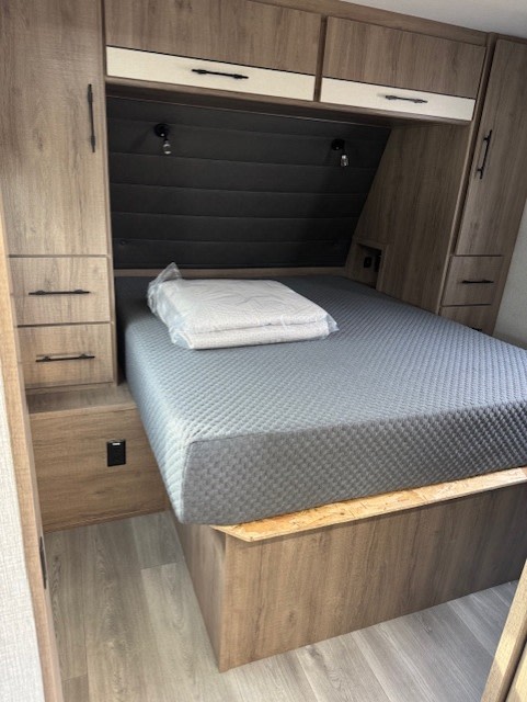 RV rental bedroom: Compact and functional with a grey bed, overhead cabinets, and side storage.. Grand Design Imagine 2024