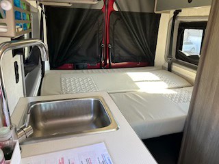 RV rental campervan interior with a compact sink area and adaptable bed setup, perfect for road trips and adventurers.. Winnebago Solis 2021