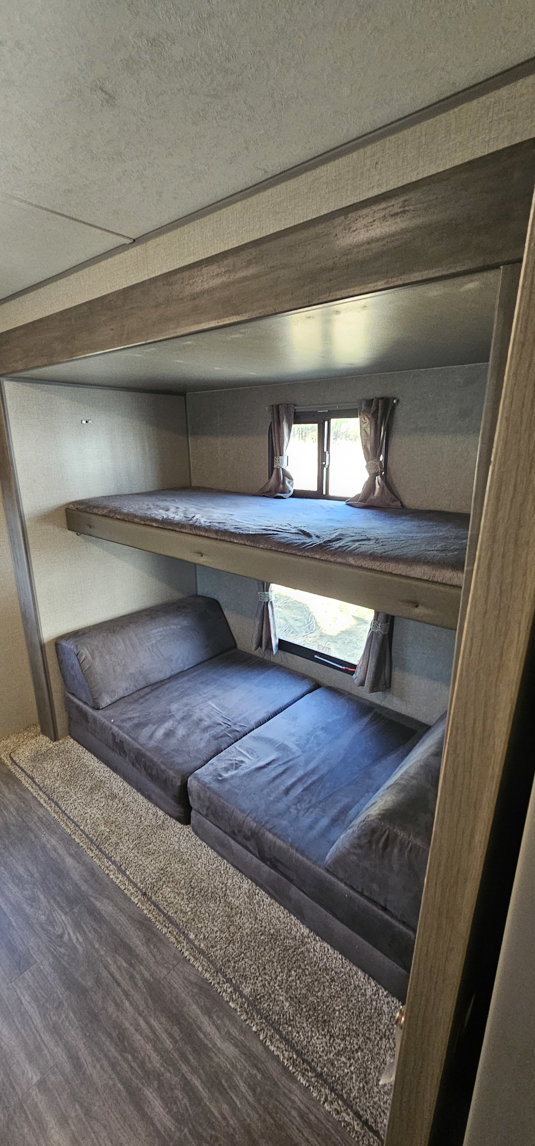 Cozy RV rental interior featuring bunk beds and a convertible seating area with windows. Ideal for family comfort.. Forest River Aurora 2022