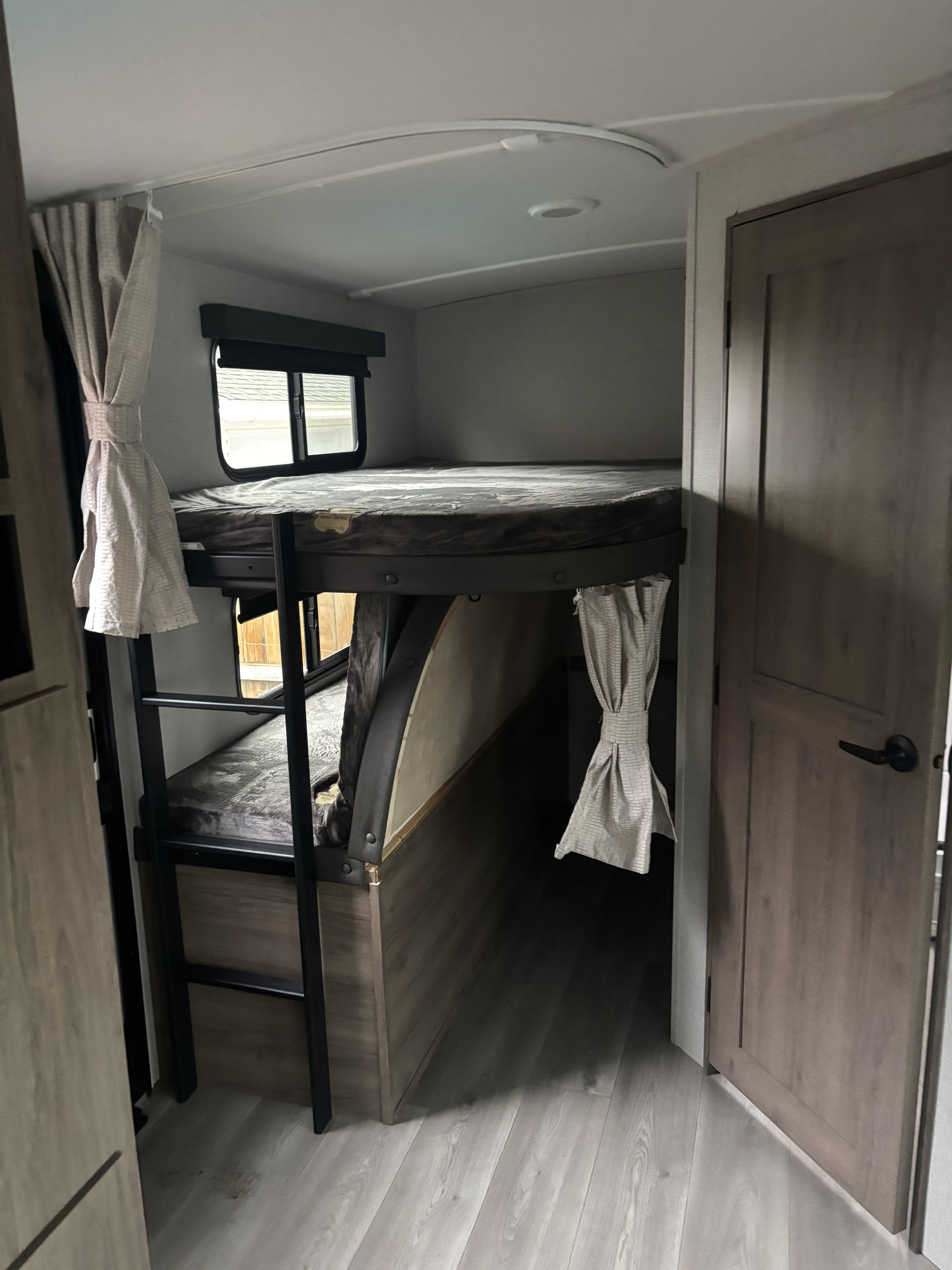 RV rental interior with stacked bunk beds, a ladder, and a window, designed for compact travel comfort.. Grand Design Imagine 2800bh 2025