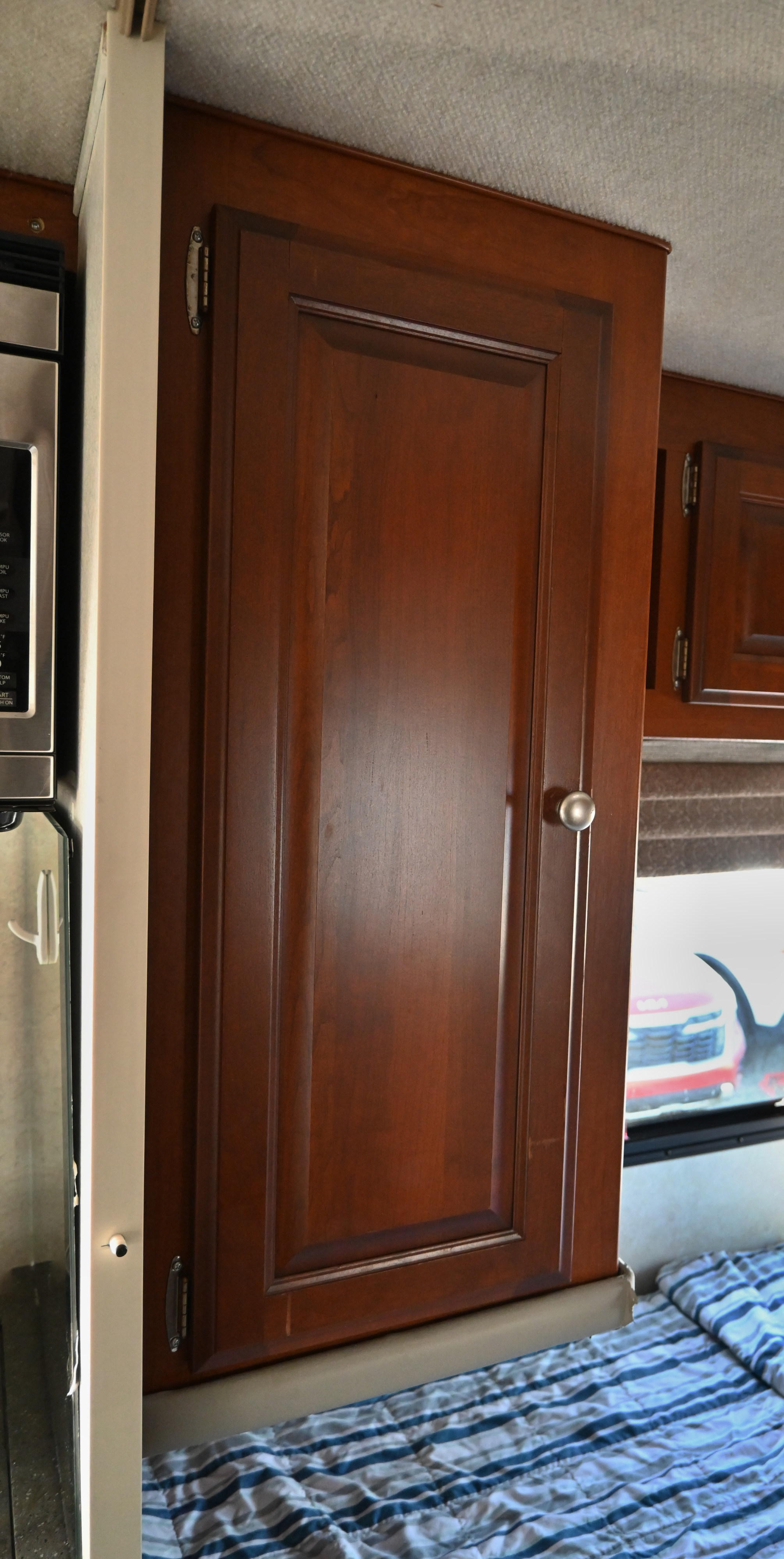 Inside an rv rental: a wooden storage cabinet, microwave, and bed highlight efficient, compact living space.. Phoenix Cruiser M-2350 Sprinter Slide 2012