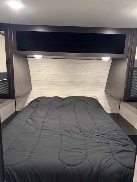 Cozy RV rental bedroom featuring a comfortable bed, overhead storage, and reading lights.. Jayco Jay Flight 2023