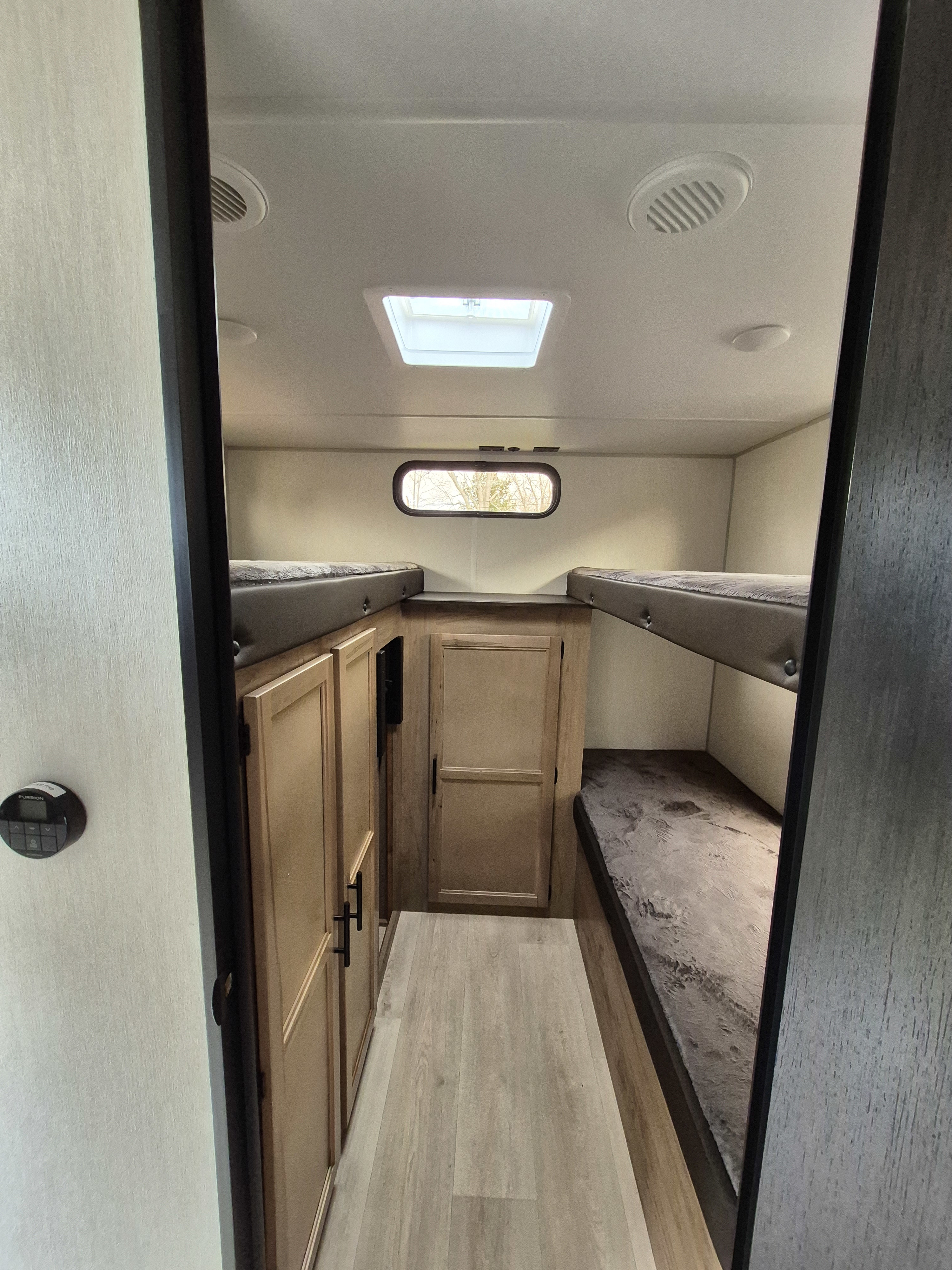 RV rental bunk room with dual bunk beds, wooden storage, and a control panel. A compact, comfortable sleeping area.. Forest River Cherokee Grey Wolf 29te 2025