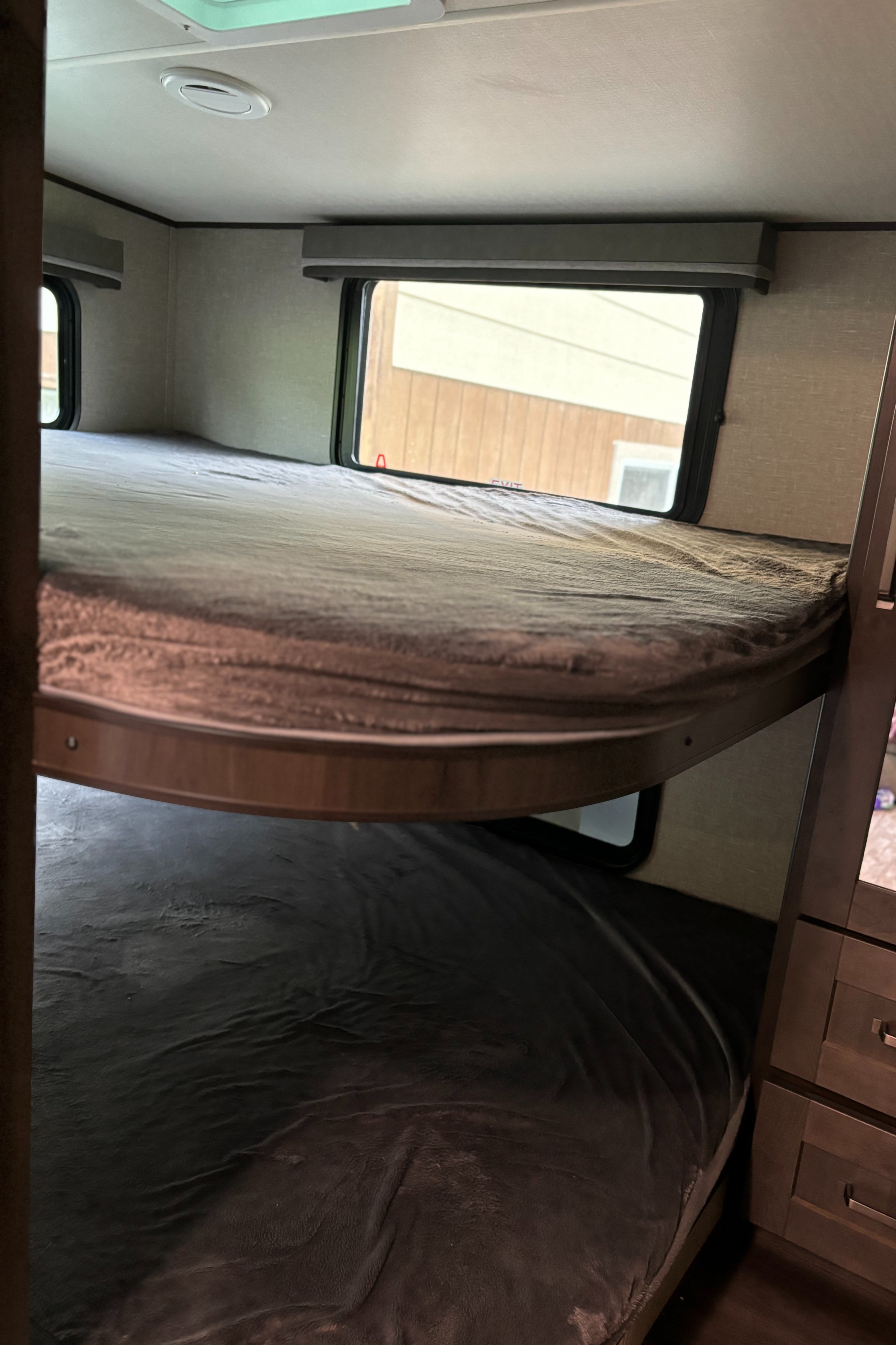 RV rental interior: upper and lower bunk beds, neatly made. Windows offer outdoor views and natural light.. Grand Design Reflection 150 2022