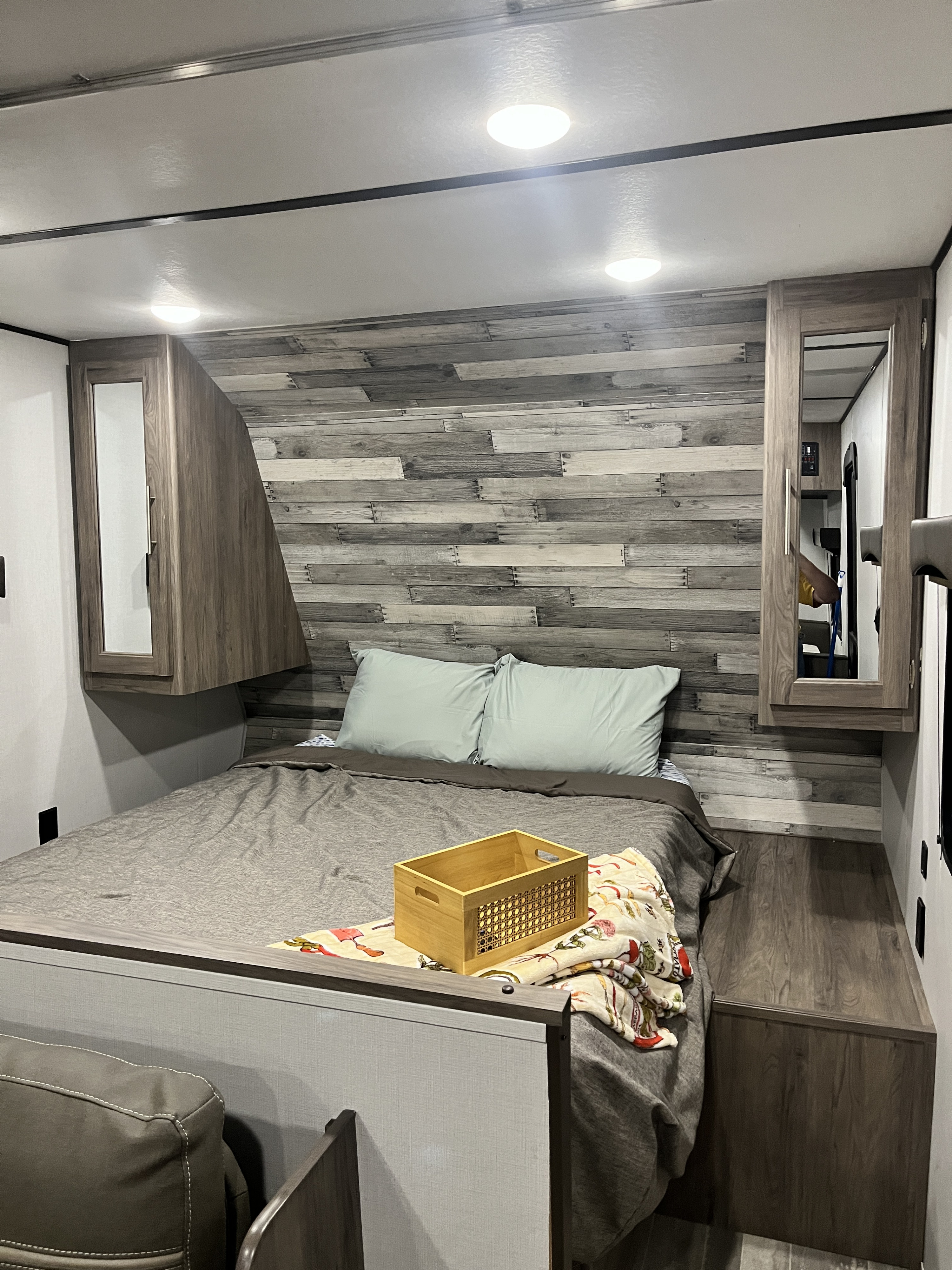 Cozy RV rental bedroom with rustic wood accent wall, built-in storage, and comfy bed for travel.. Crossroads RV Zinger Lite 2021