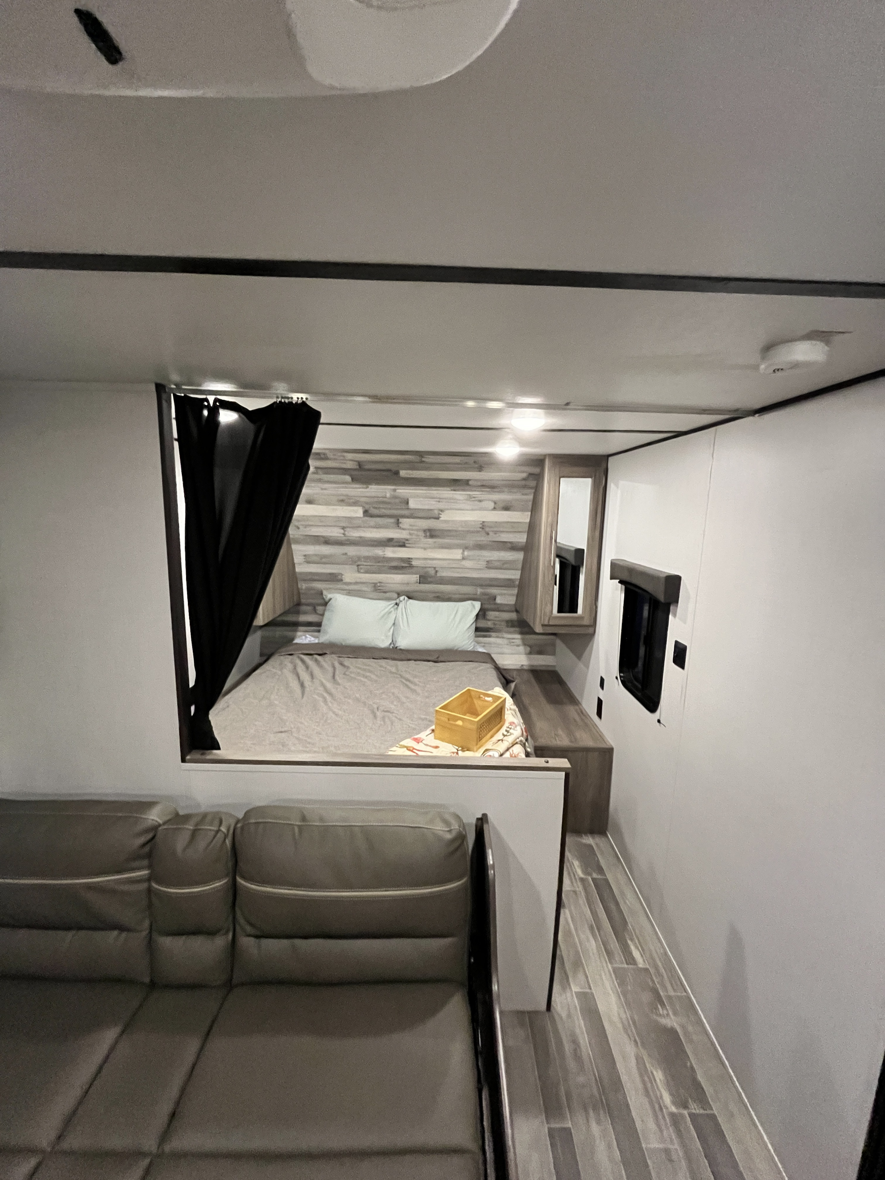 Cozy RV rental interior showing a bed with pillows and a sofa. Modern design for comfortable travel.. Crossroads RV Zinger Lite 2021