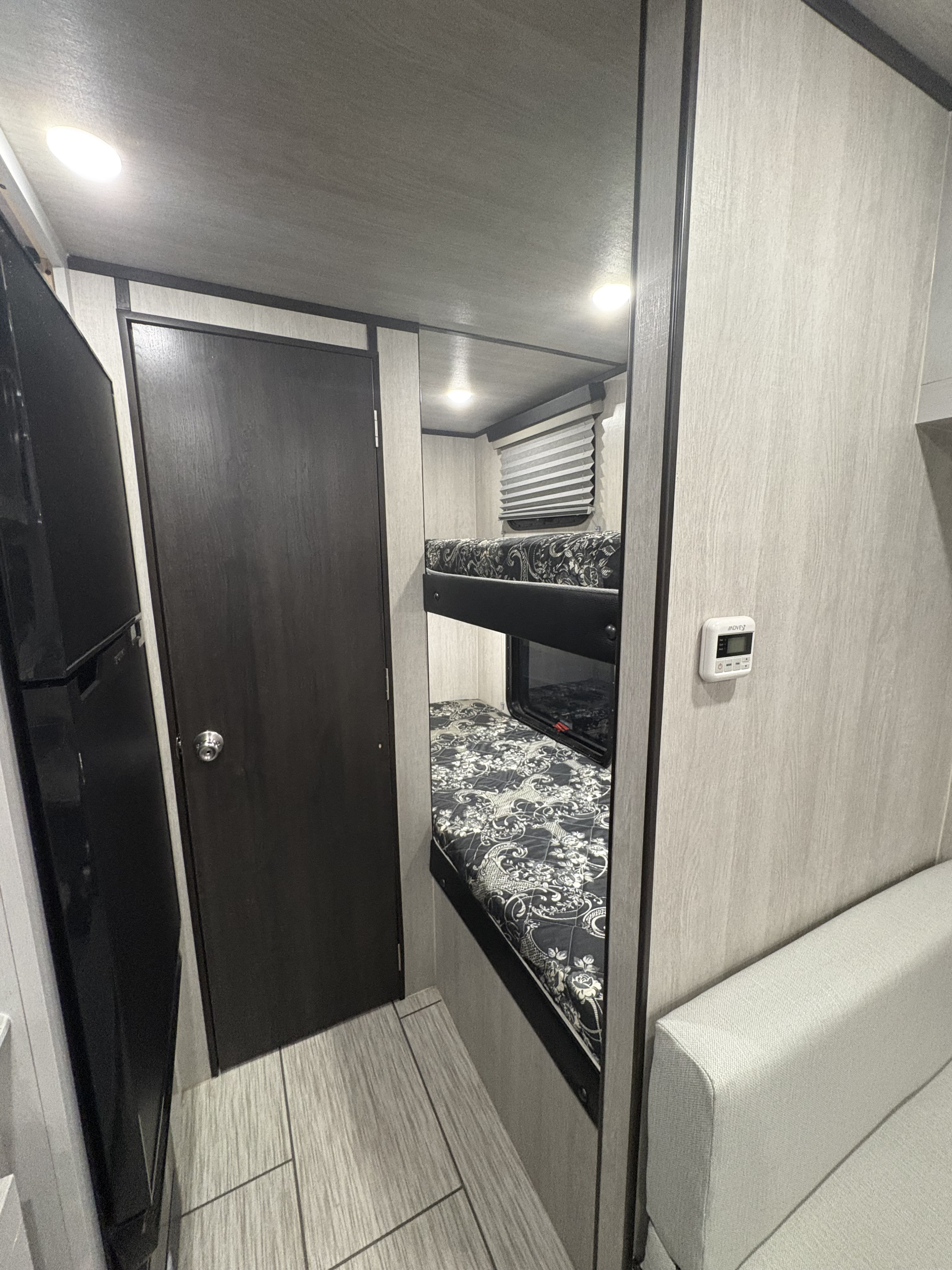 RV rental interior: two bunk beds, refrigerator, and light couch, showcasing a compact and functional layout.. Genesis supreme Surf side limited 16bb 2023