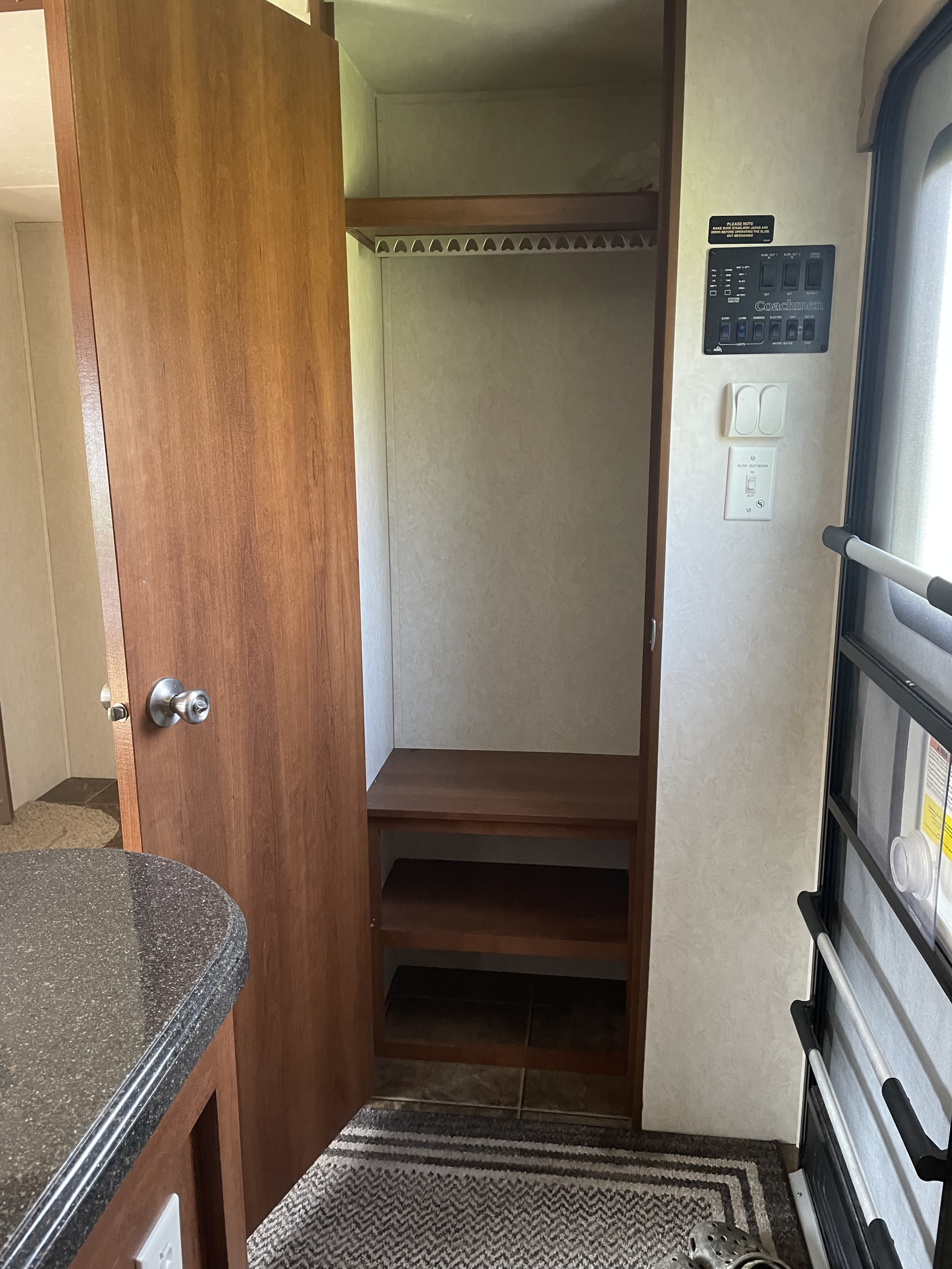RV rental interior shows an open closet with hanging bar and shelves, a Coachmen control panel, and light switches for a comfortable stay.. Coachmen Freedom Express Liberty Edition 320BHDS 2014
