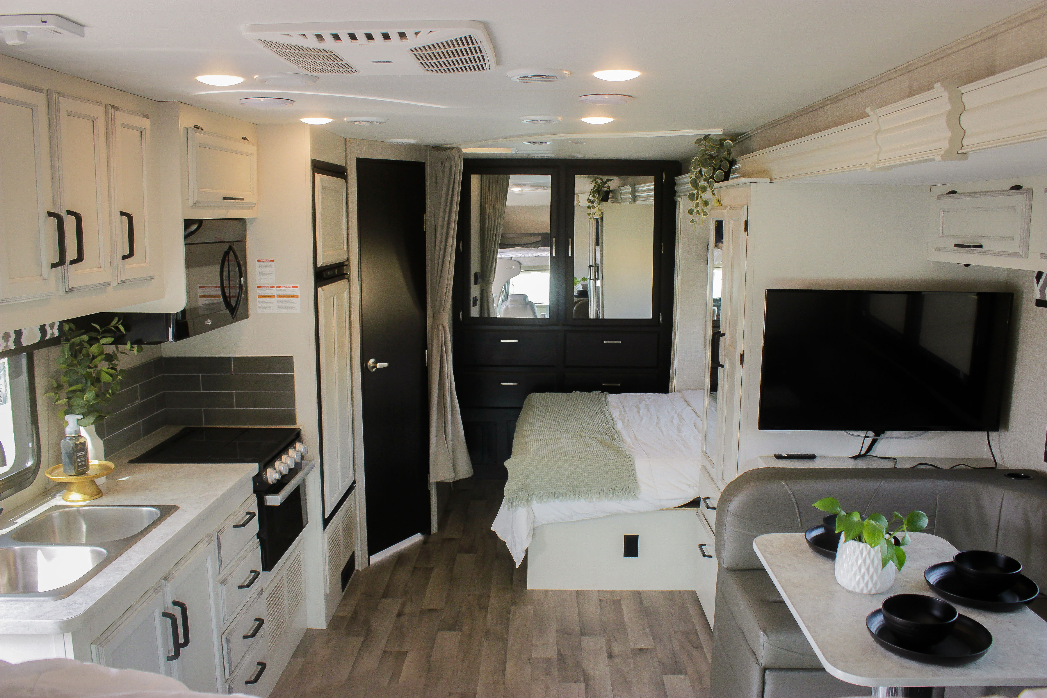 Bright RV rental interior showcasing a modern kitchen, comfortable bed, mirrored wardrobe, and dining area.. Jayco Redhawk 2022