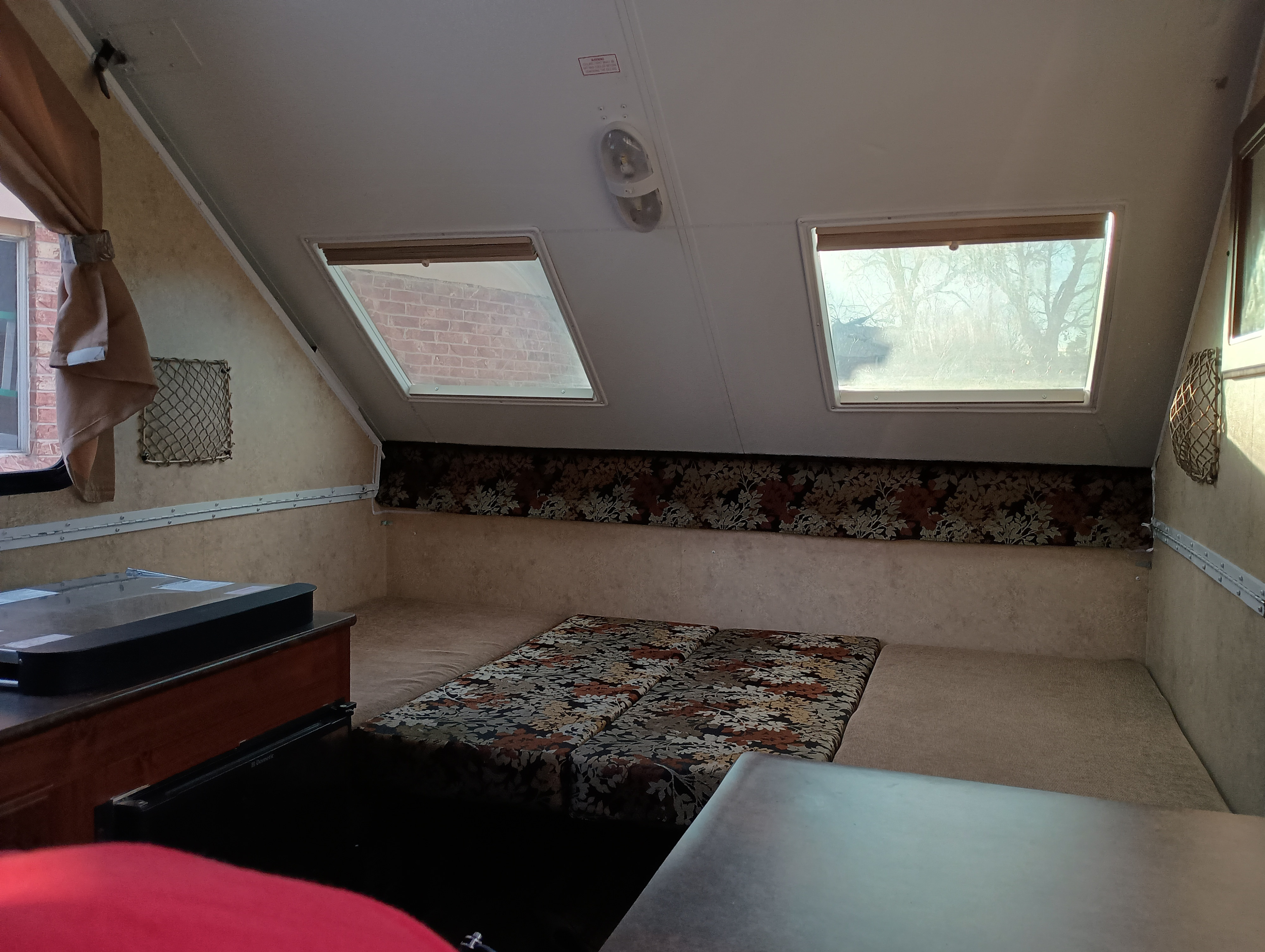 Inside an RV rental: a bright, spacious sleeping area with patterned cushions, skylights, and compact kitchenette.. Forest River Flagstaff Classic 2014