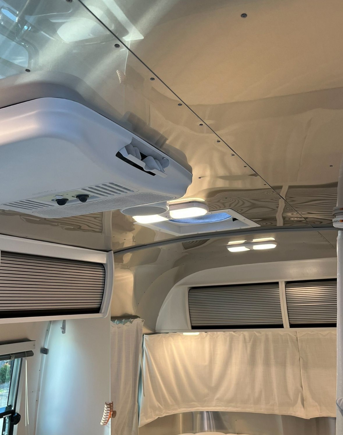 Inside an RV rental: a modern, metallic ceiling with integrated AC, bright lights, and storage. Perfect for your next travel adventure.. Airstream Bambi 2021