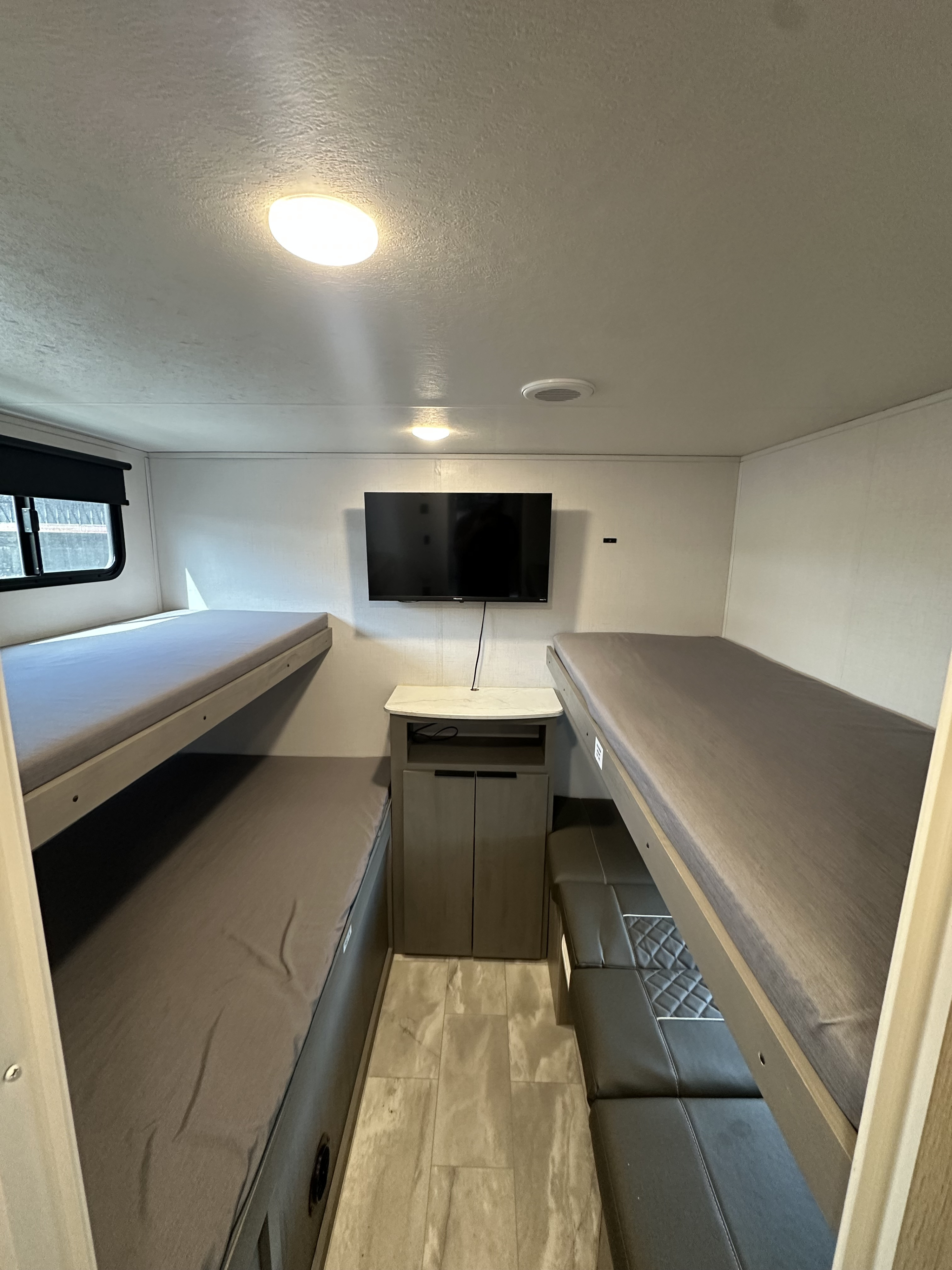 RV rental bunkhouse featuring four comfortable beds, a wall-mounted TV, and central storage, ideal for families.. Dutchmen Kodiak SE 2024