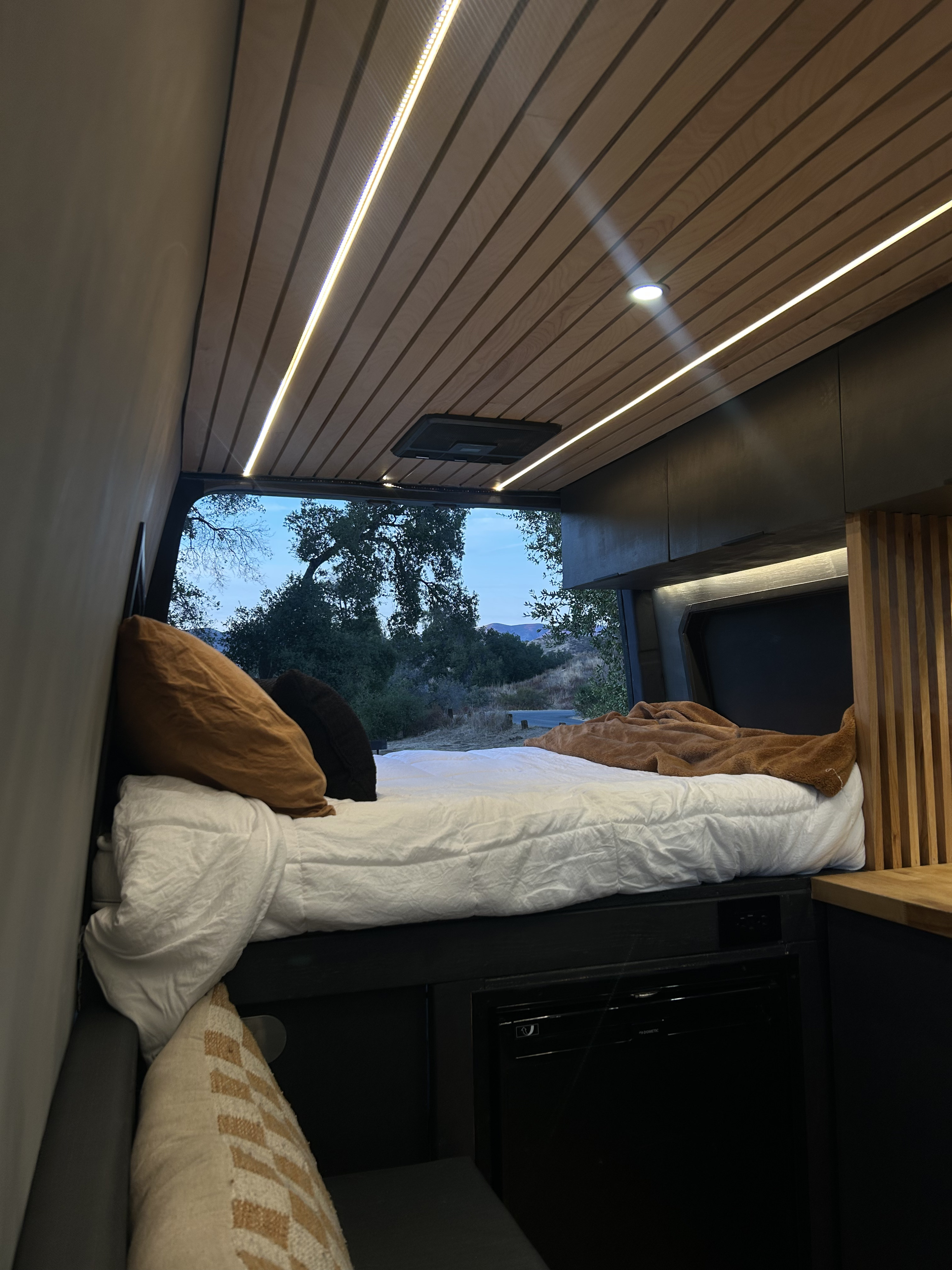Cozy RV rental interior with bed & ambient lighting, perfect for van life adventures with a view.. Mercedes-Benz Sprinter 2022