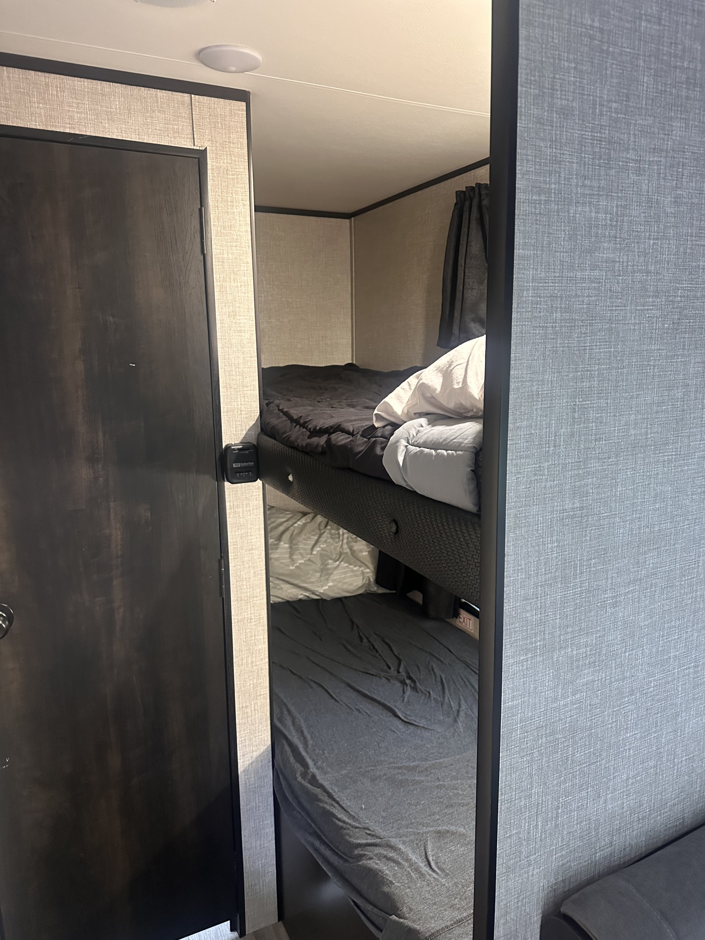 View inside an RV rental showing two stacked bunk beds with dark bedding, offering compact sleeping space.. Jayco Jay Flight 2022