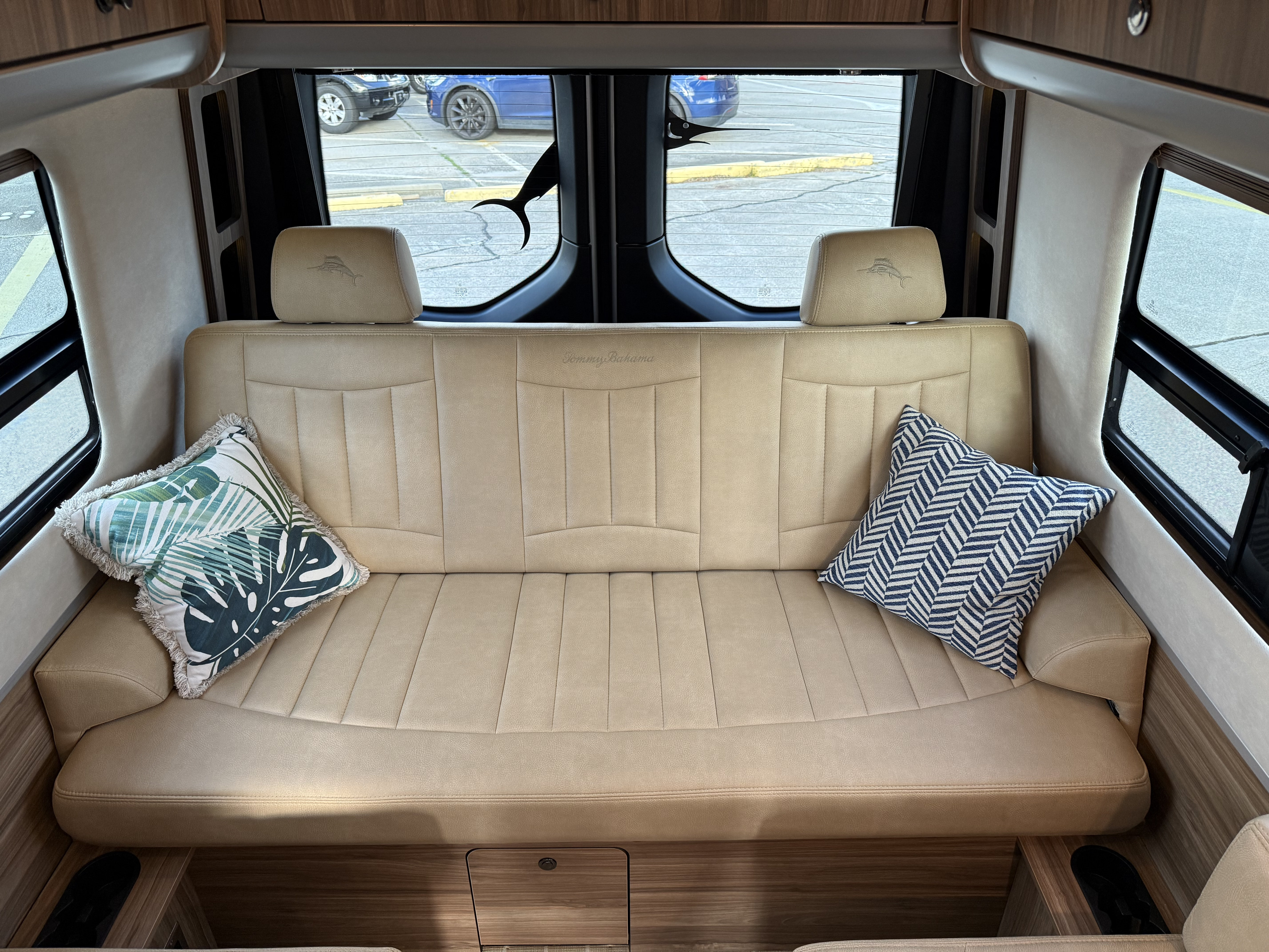 This RV rental offers a luxurious beige sofa with embroidered marlin headrests, tropical/chevron pillows, and a rear window view.. Airstream Interstate 2023