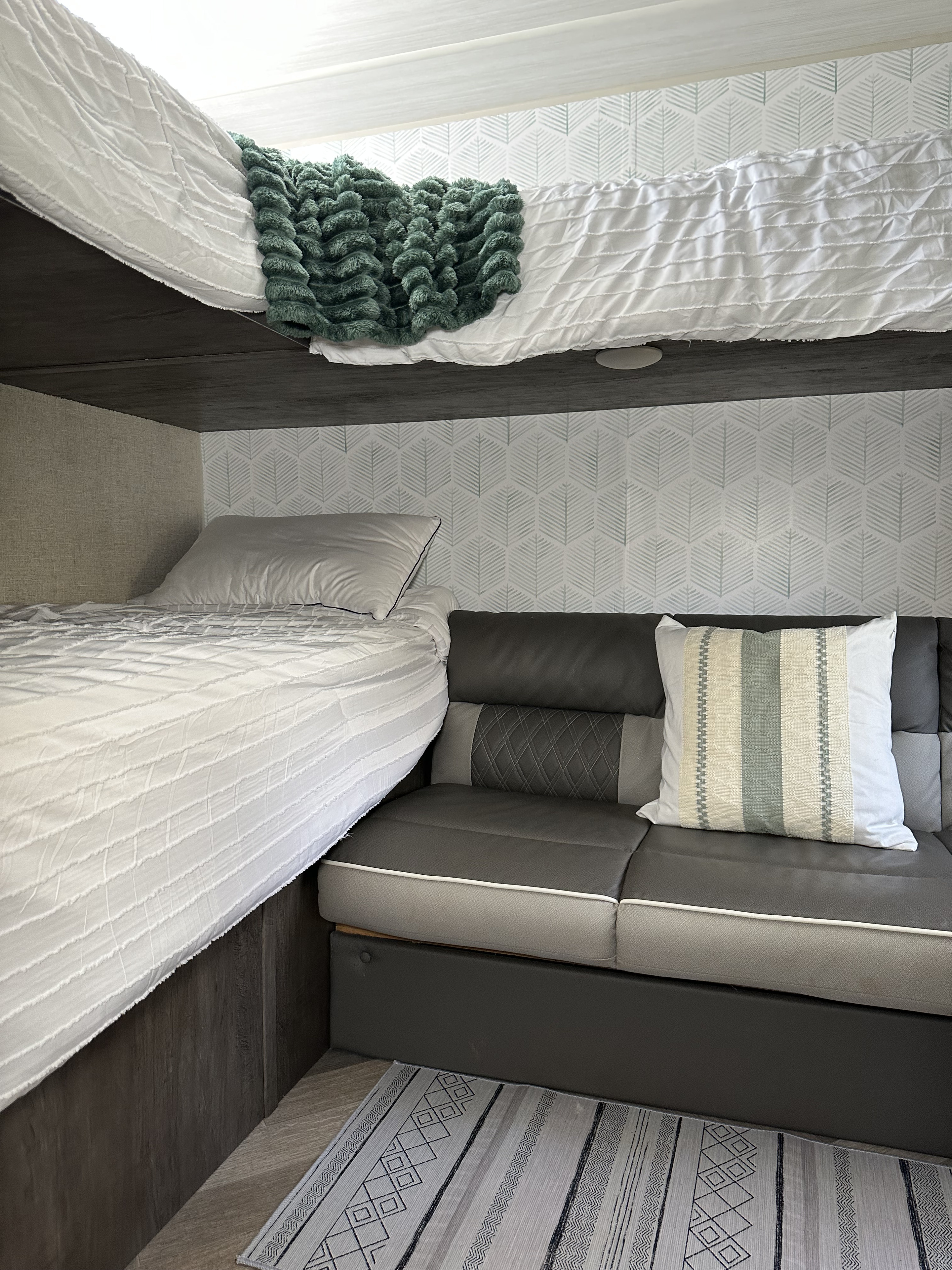 Cozy RV rental interior with bunk beds, a stylish sofa, and decorative accents, perfect for a comfortable stay.. Forest River Salem Cruise Lite 2021