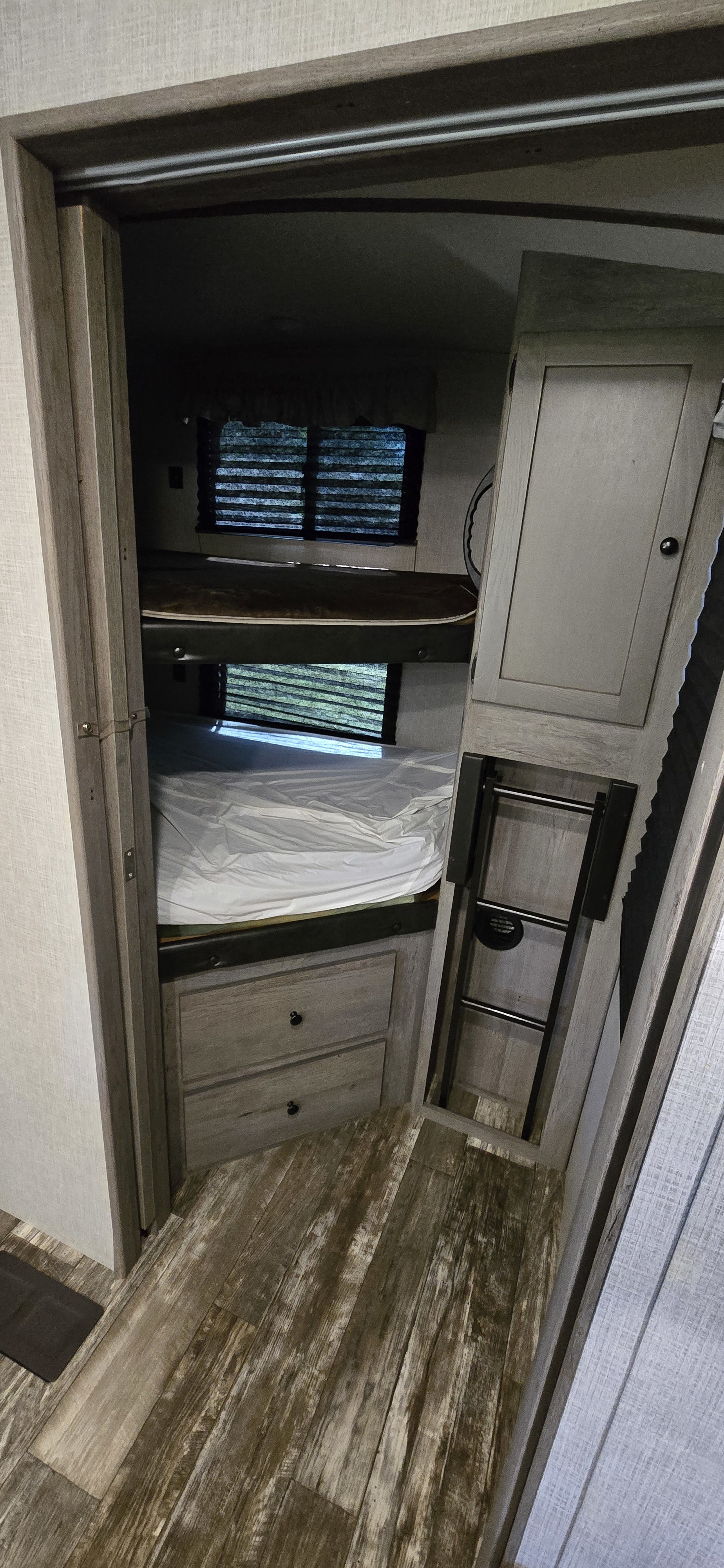 Explore this RV rental's bunkhouse, featuring stacked beds, storage drawers, a ladder, and window blinds.. Keystone RV Outback Ultra-Lite 2020