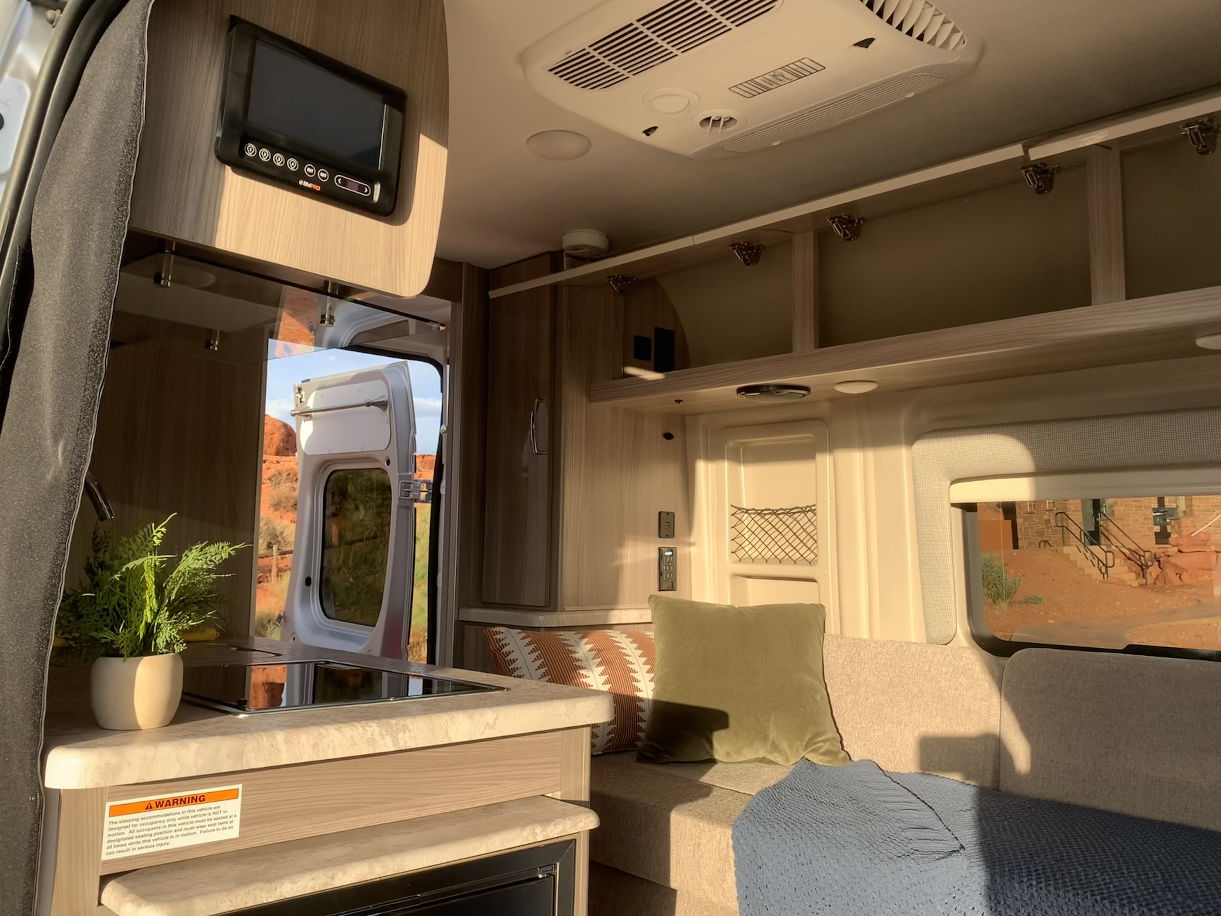 Inside an **rv rental**: A modern kitchen, comfortable seating area, and tech controls for a mobile adventure, with desert views.. Thor Motor Coach Scope 2023