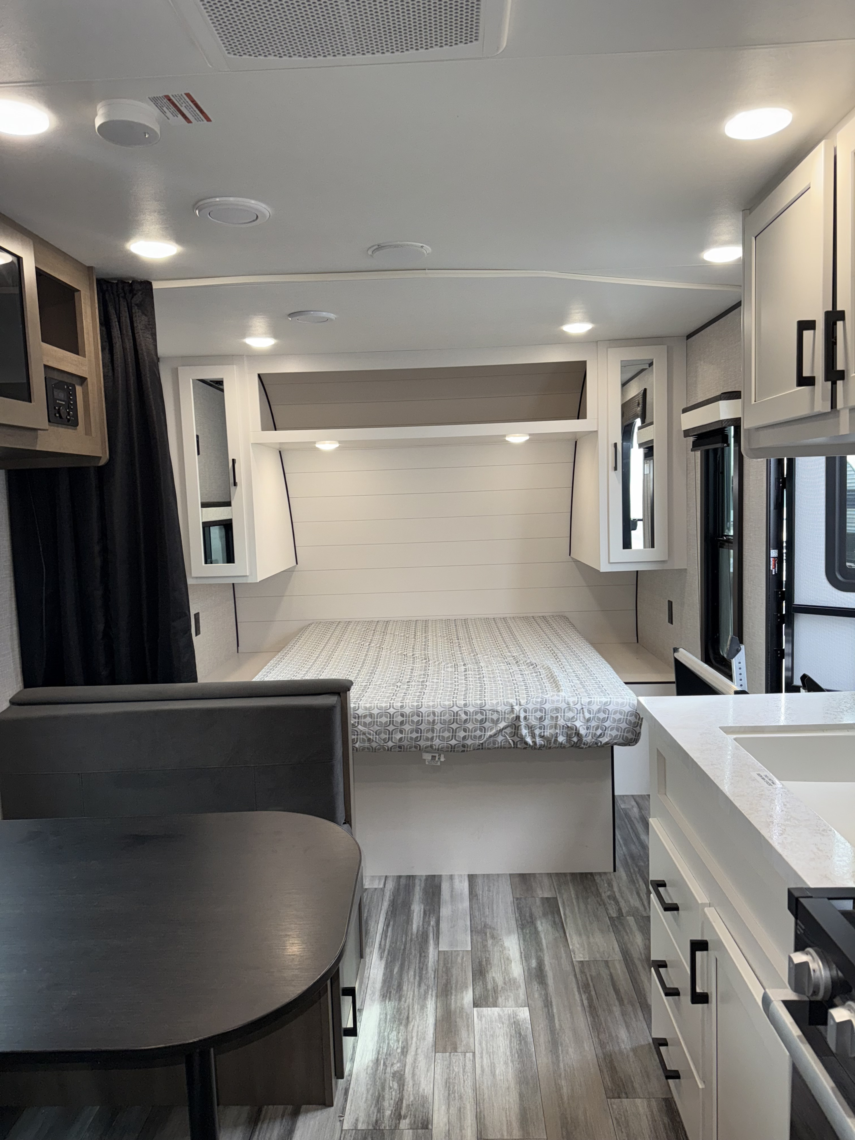 Inside this RV rental: a compact living space with a bed, dinette, kitchen, and modern white cabinetry. Ideal for travel.. Jayco Jay Flight 2024