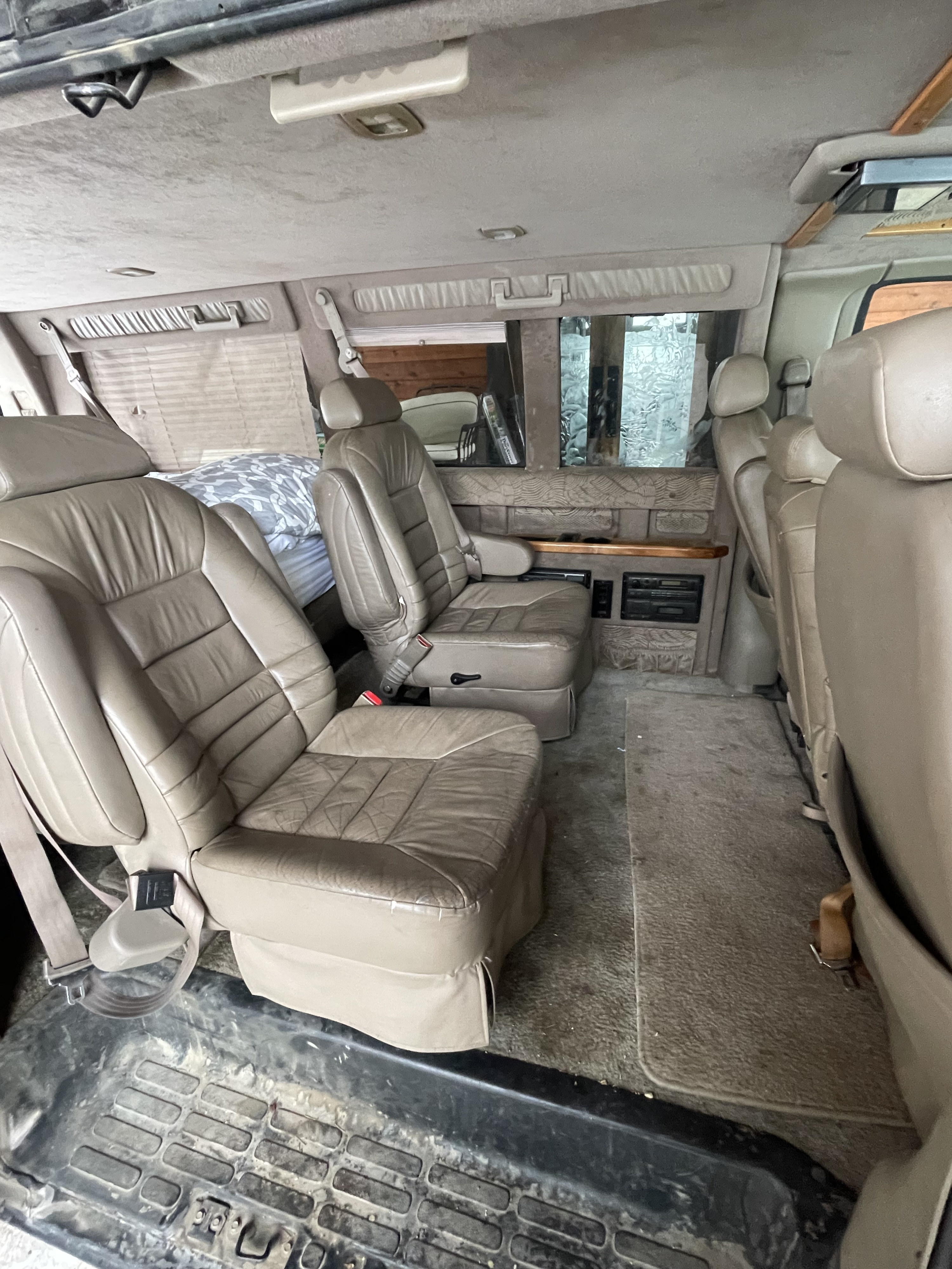 Spacious RV rental interior featuring comfortable leather seats, a sleeping area, and entertainment features. Ideal for road trips.. Chevrolet Express Van 1999