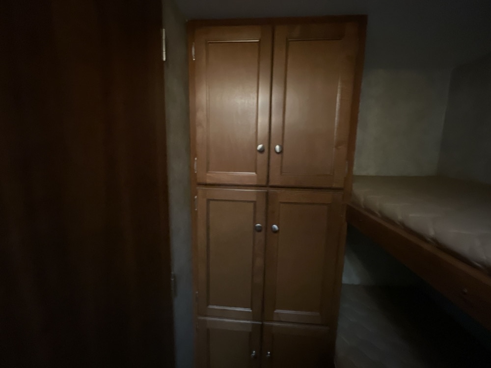 Inside an RV rental featuring wooden storage cabinets and comfortable bunk beds, perfect for family adventures.. Keystone RV Bullet Ultra Lite 2014