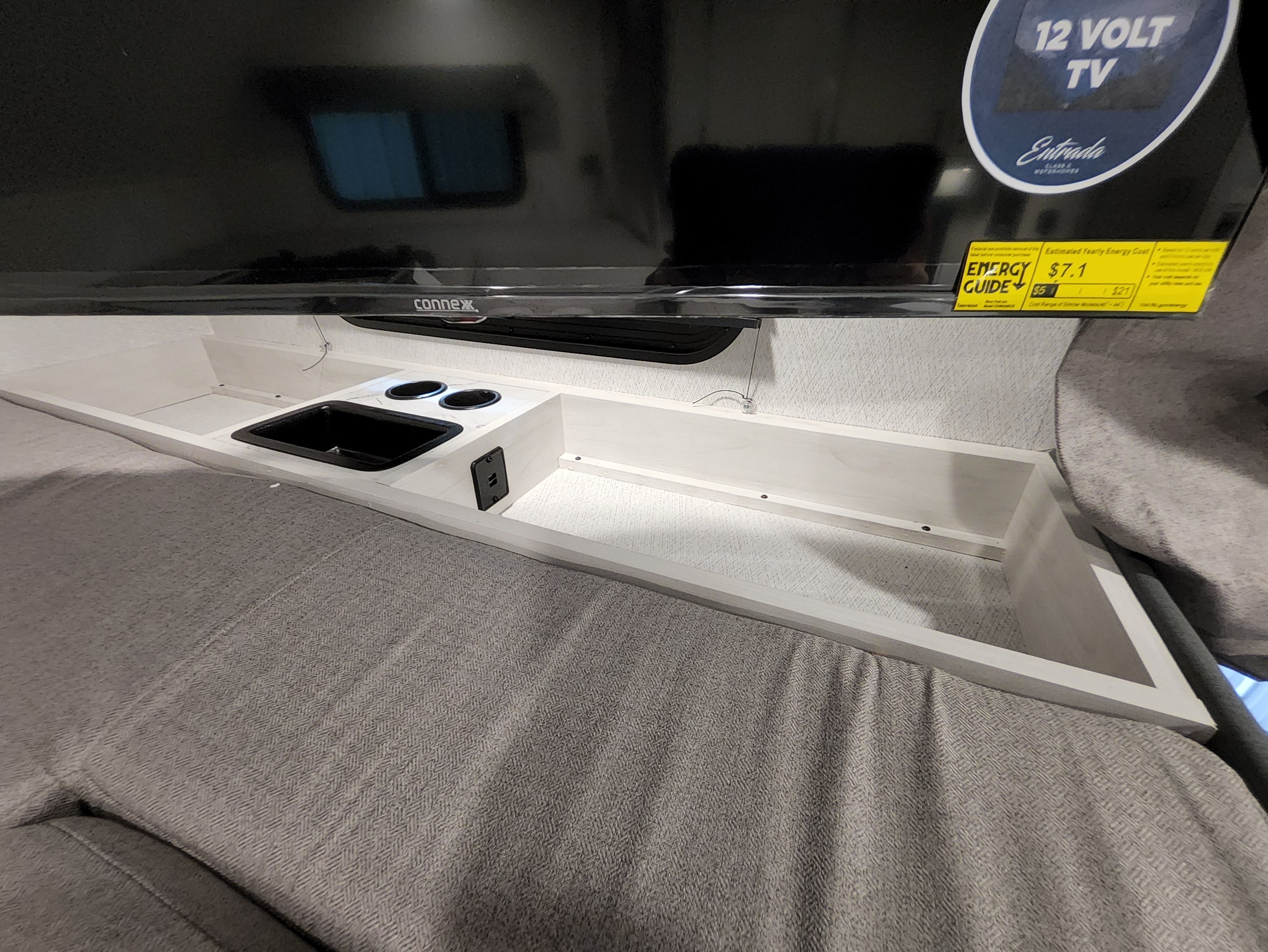 Inside an rv rental: a comfy bed, wall-mounted Connex 12V TV, and bedside console with basin, cupholders, and USB.. East To West Entrada 2000NS 2025