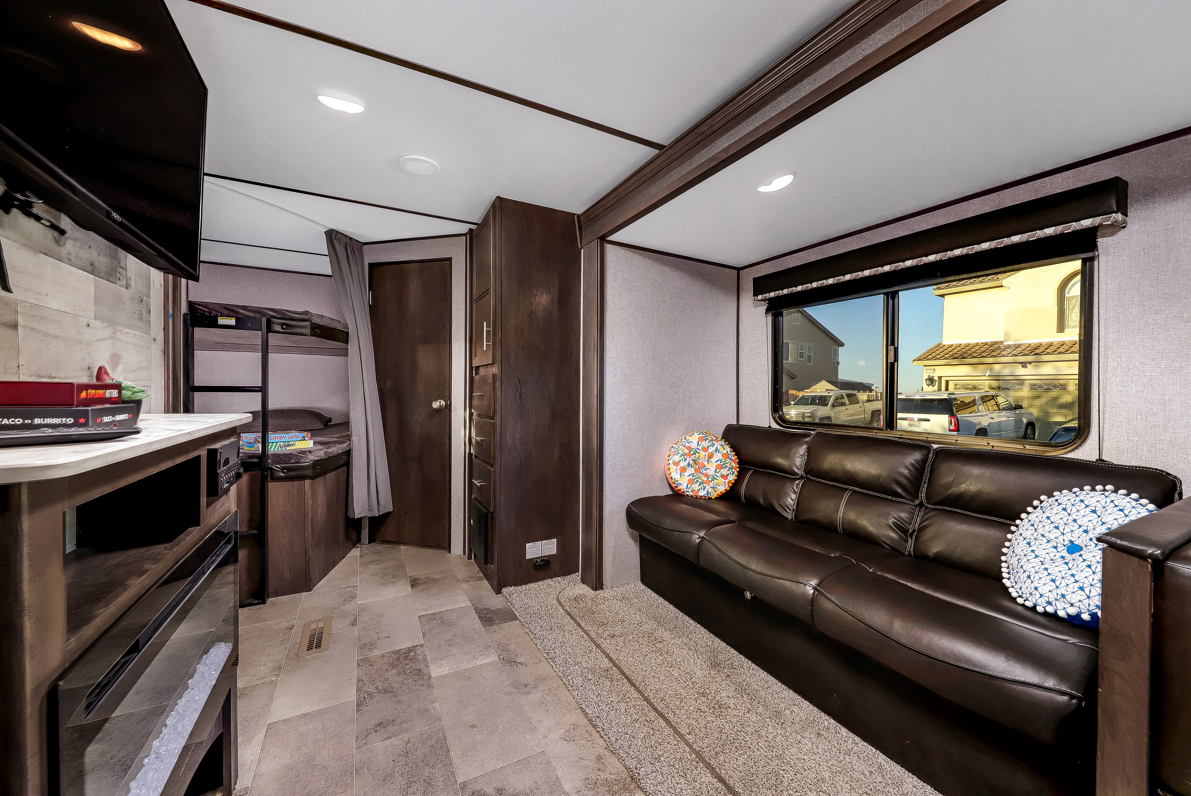 Discover this cozy RV rental's inviting interior: dark sofa, entertainment counter with TV, bunk beds, and wood accents.. Dutchmen Coleman 2021