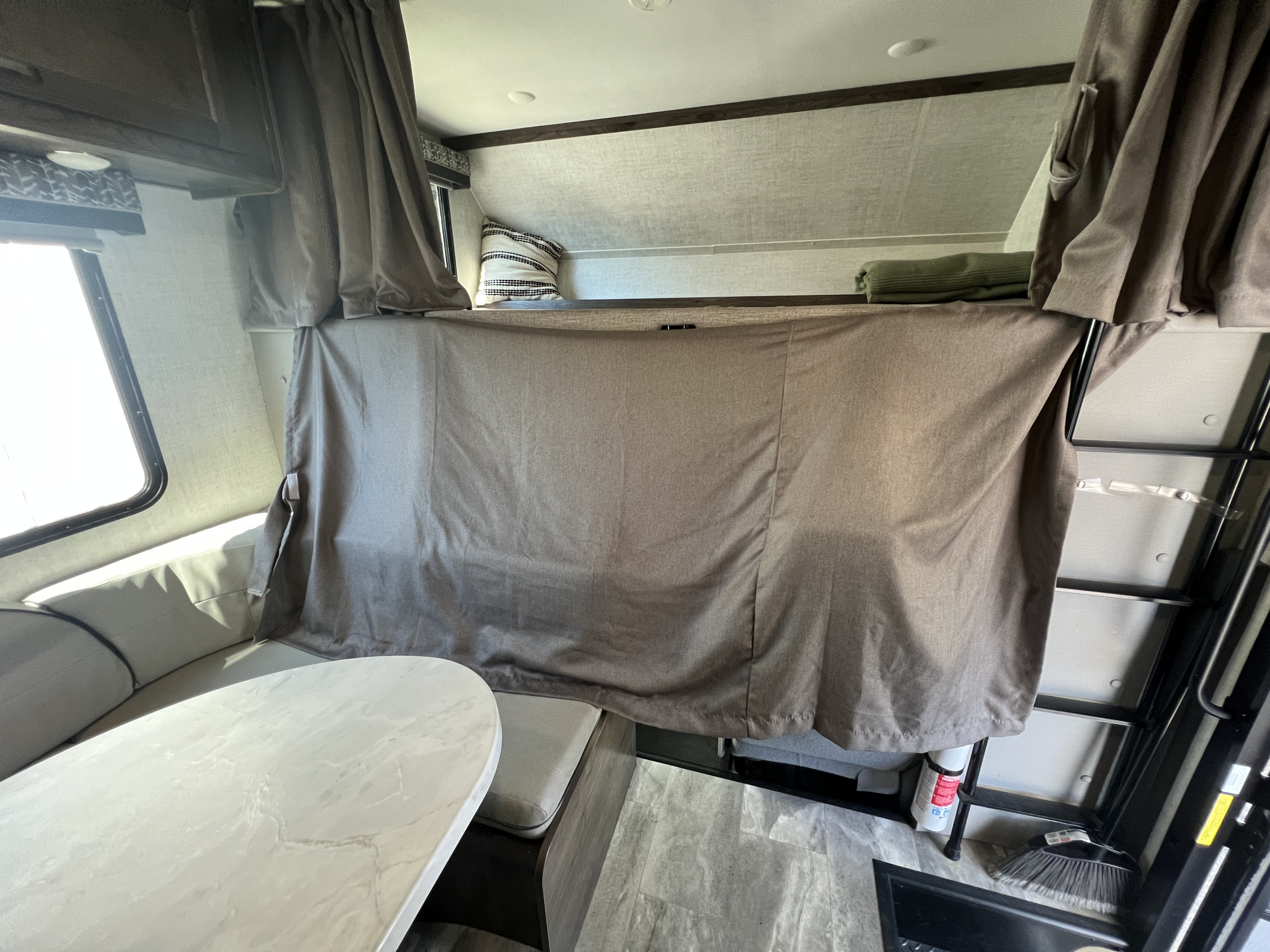 Cozy RV rental interior featuring a bunk bed with privacy curtain and a dinette area with seating and a table.. Gulf Stream Conquest 2023