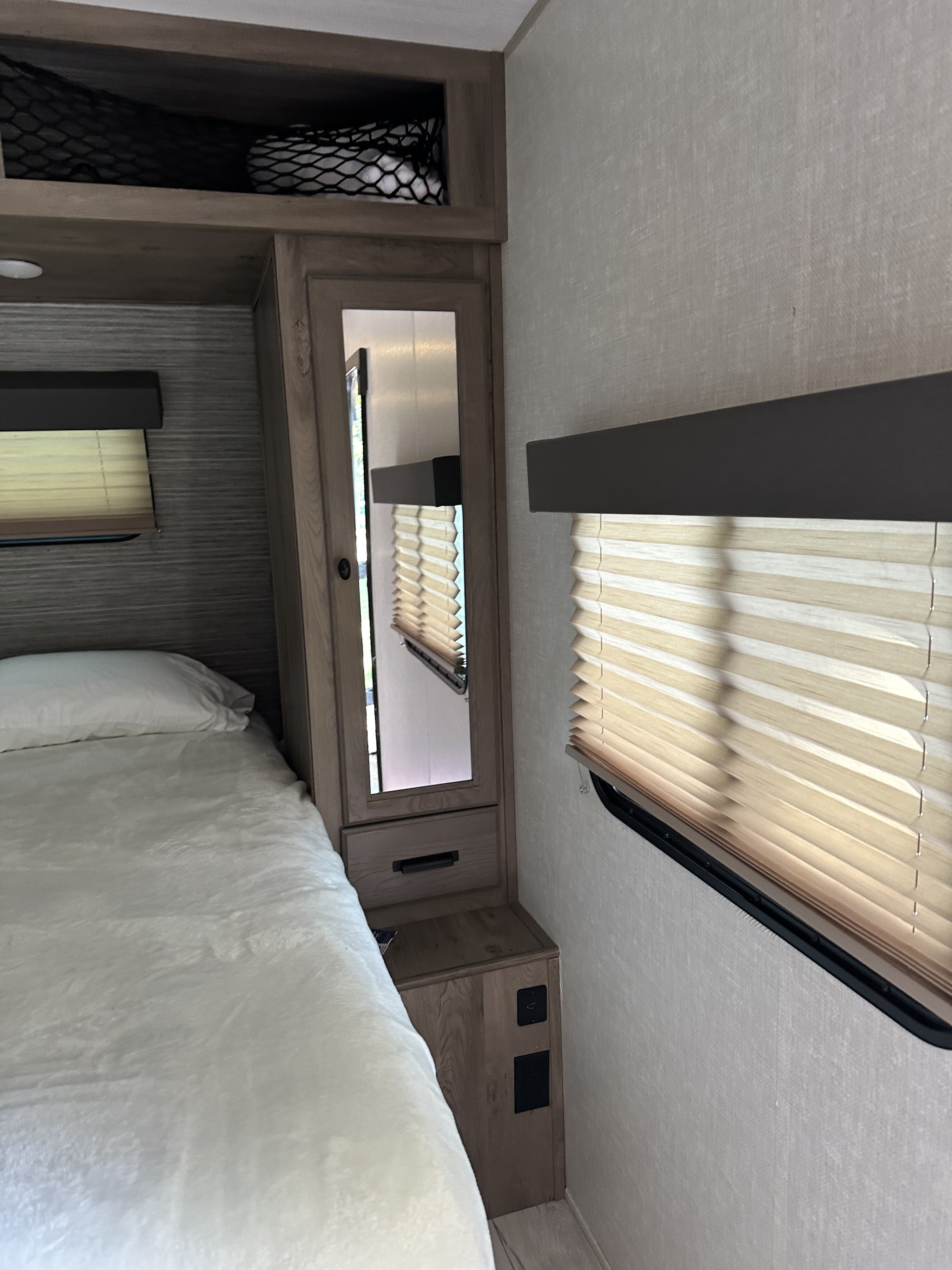This RV rental's bedroom features a comfortable bed, mirrored closet, window blinds, and handy USB outlets.. Keystone RV Springdale 2020