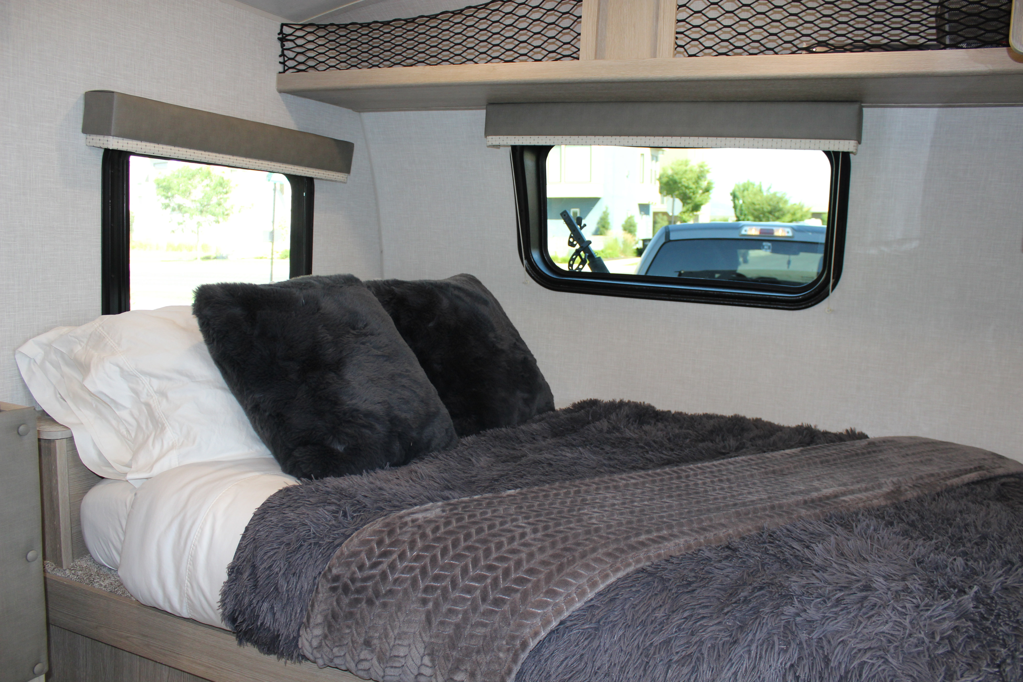 Cozy RV rental bedroom with soft gray bedding and window views, perfect for comfortable travel accommodation.. Forest River Rockwood GeoPro 2019