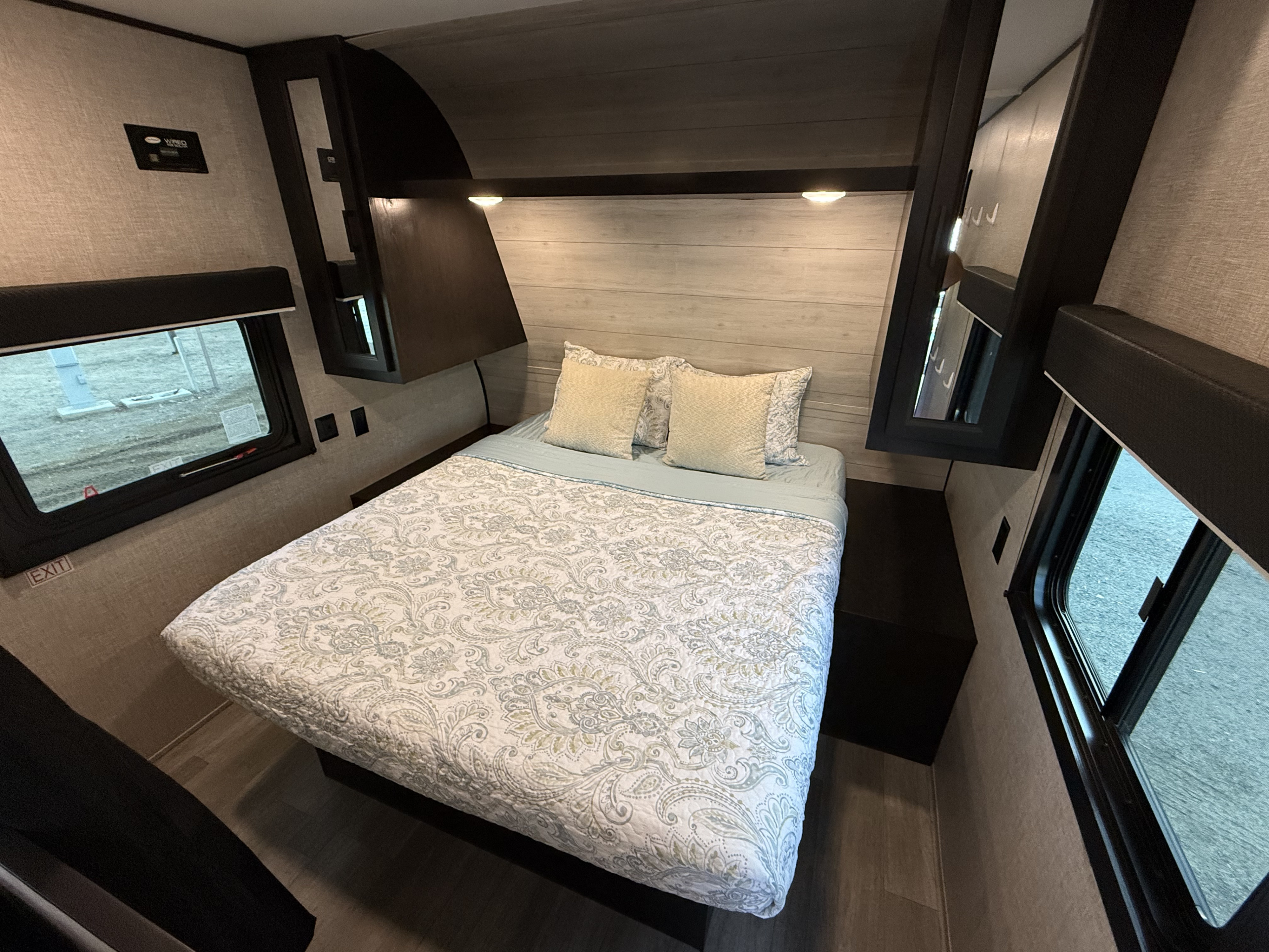This RV rental's bedroom offers a cozy space with patterned bedding, reading lights, and an exit window.. Jayco Jay Flight SLX 2022