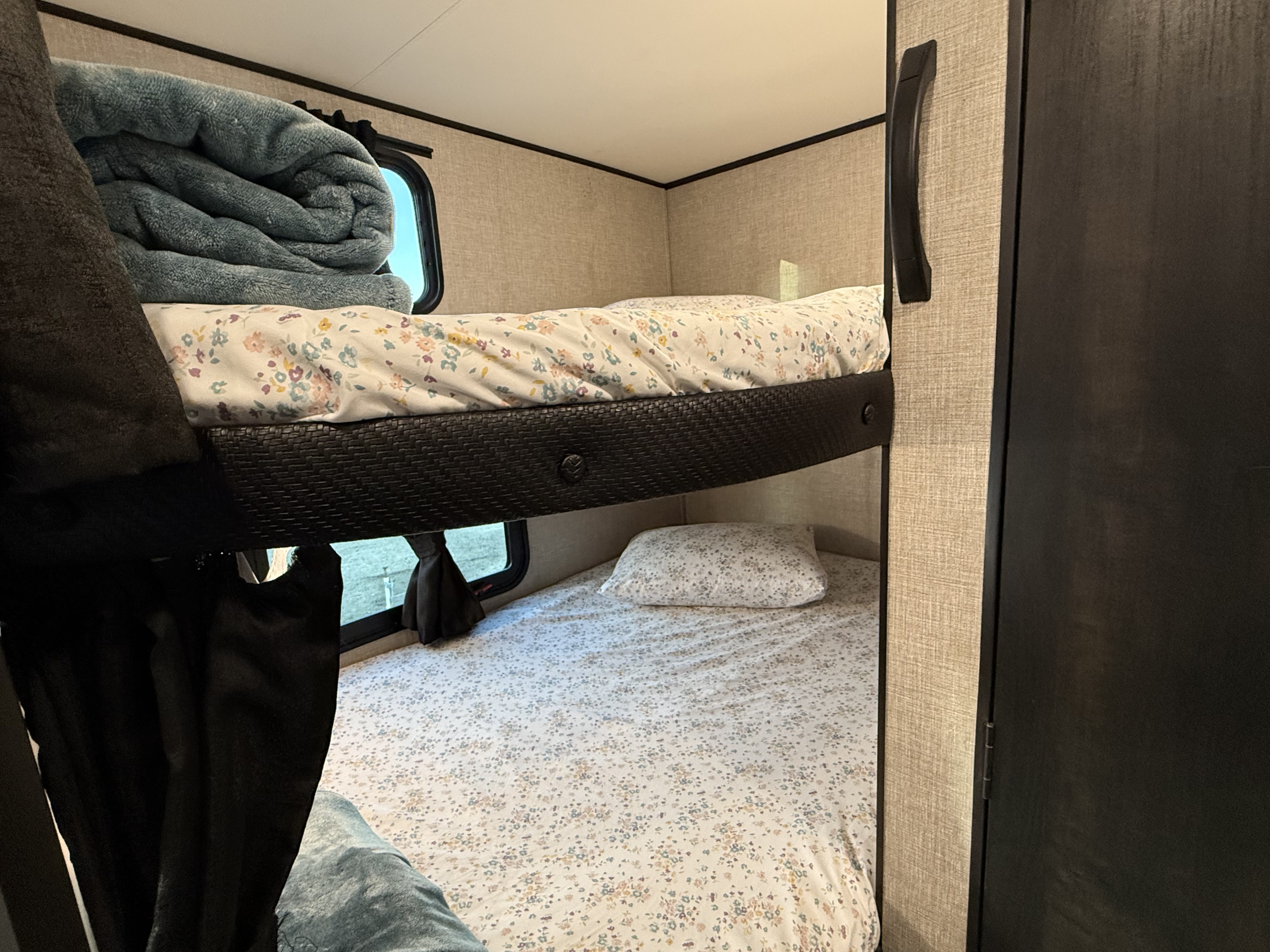 RV rental interior: two cozy bunk beds with floral sheets, wicker-textured frame, and windows for a comfy journey.. Jayco Jay Flight SLX 2022
