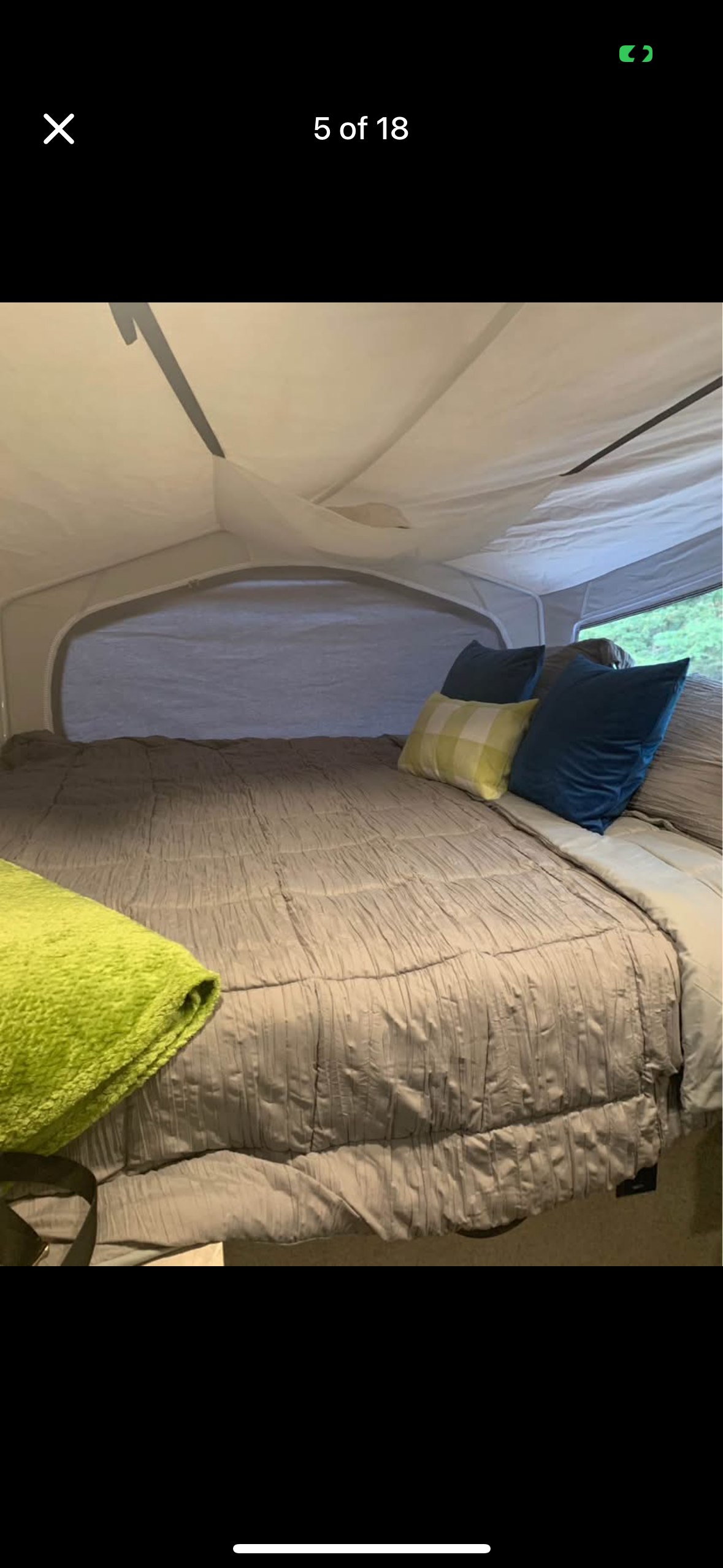 Pop-up RV rental sleeping area: a plush gray bed with blue and plaid pillows, and a bright green blanket.. Forest River Rockwood Premier 2020