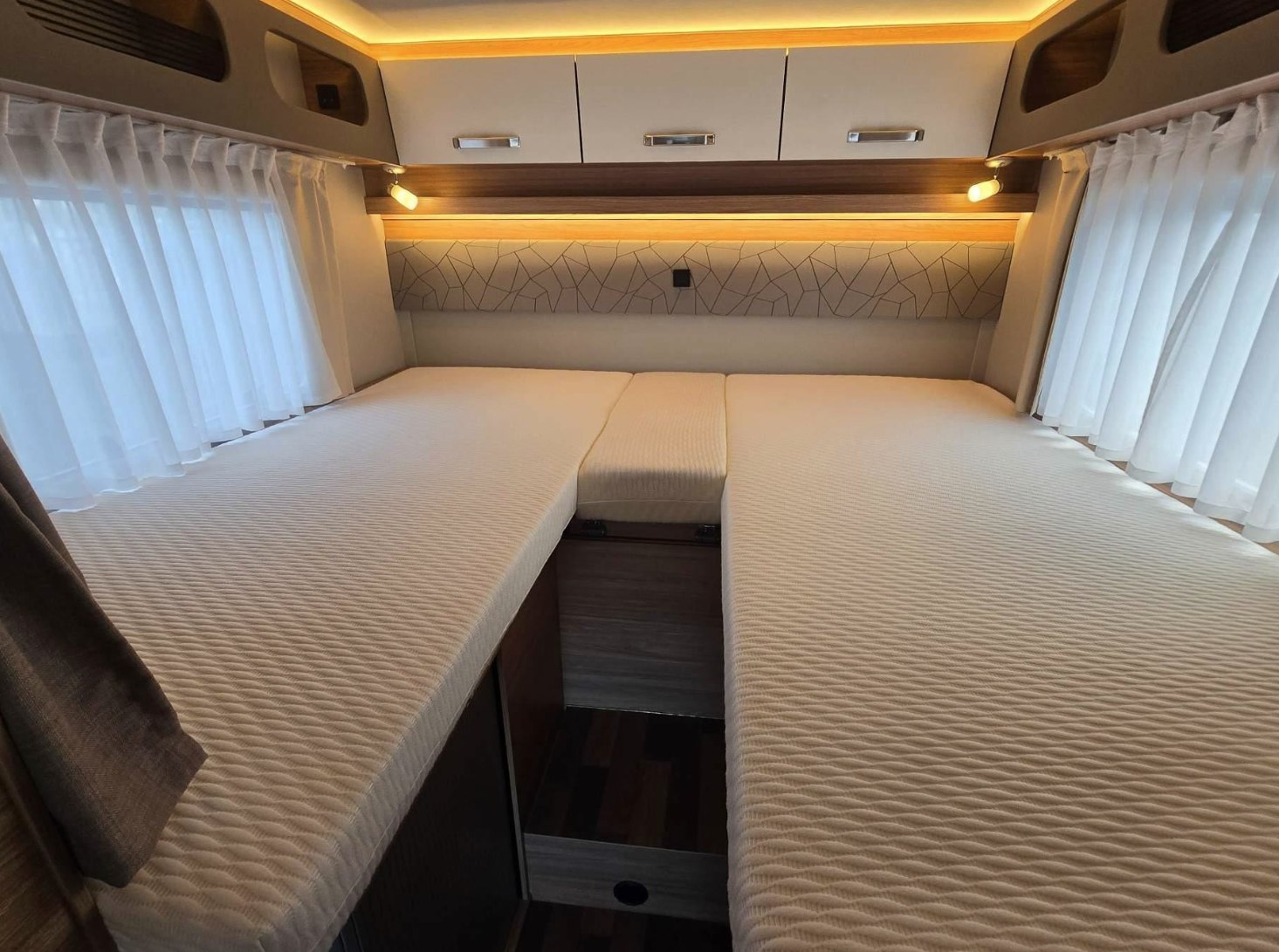 Comfortable RV rental interior with convertible twin beds and ample overhead storage, perfect for a cozy night's sleep.. Weinsberg CaraSuite 700 ME 2025