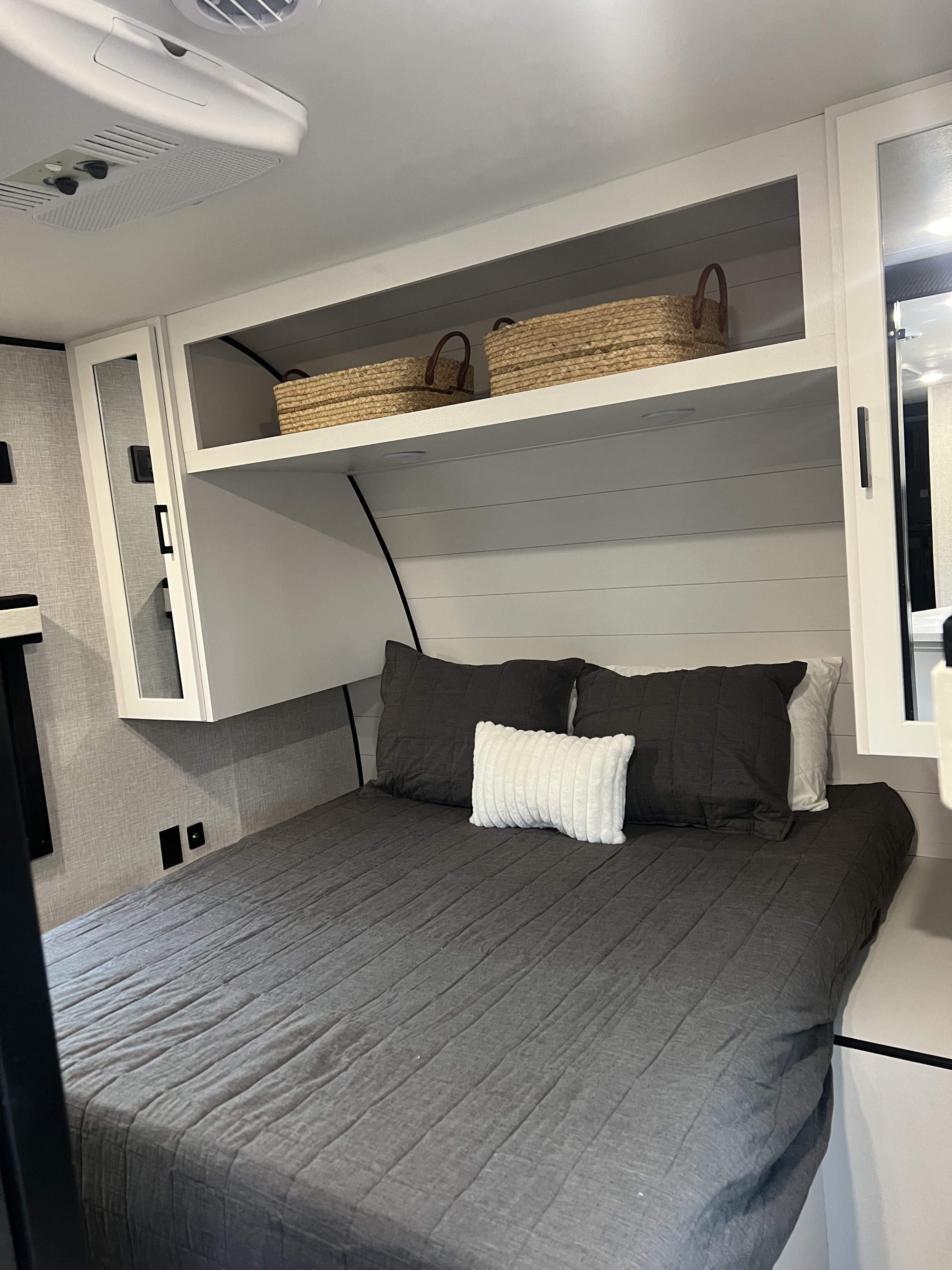 Step inside this RV rental's bedroom, showcasing dark grey bedding, overhead storage, and white shiplap walls.. Jayco Jayflight 324bds 2025