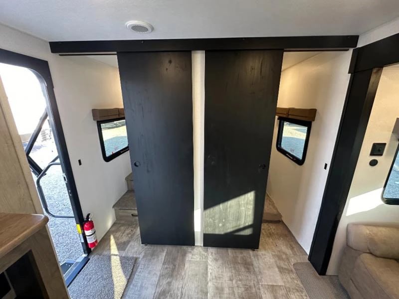 Modern RV rental interior: A stylish bunkhouse area, accessed via sleek black sliding barn doors, with steps and windows.. Palomino Puma 337BH 2025