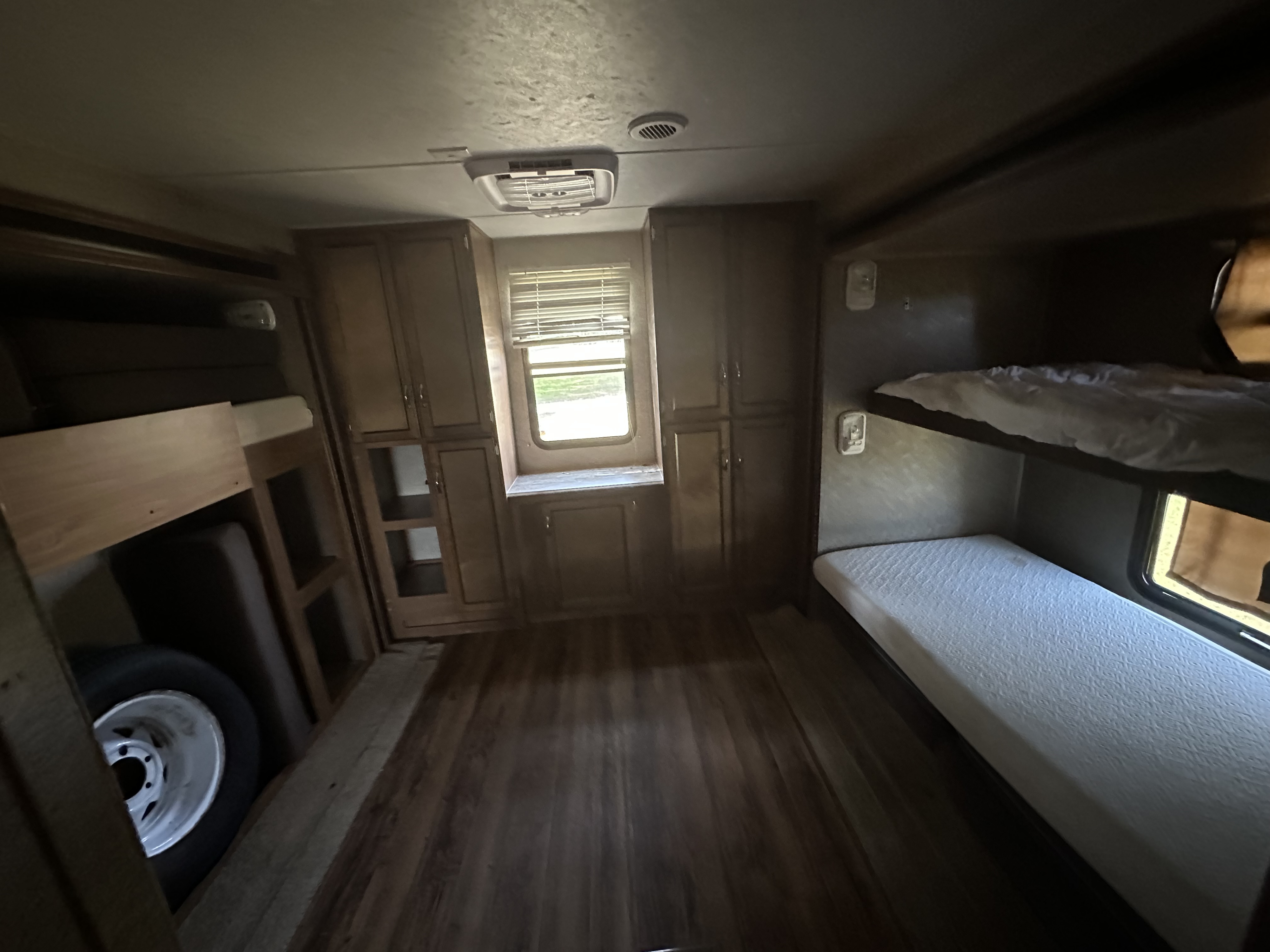 RV rental with bunk beds, built-in storage, a bright window, and a tire stored under bunks.. Coachmen 323TSQB 2016