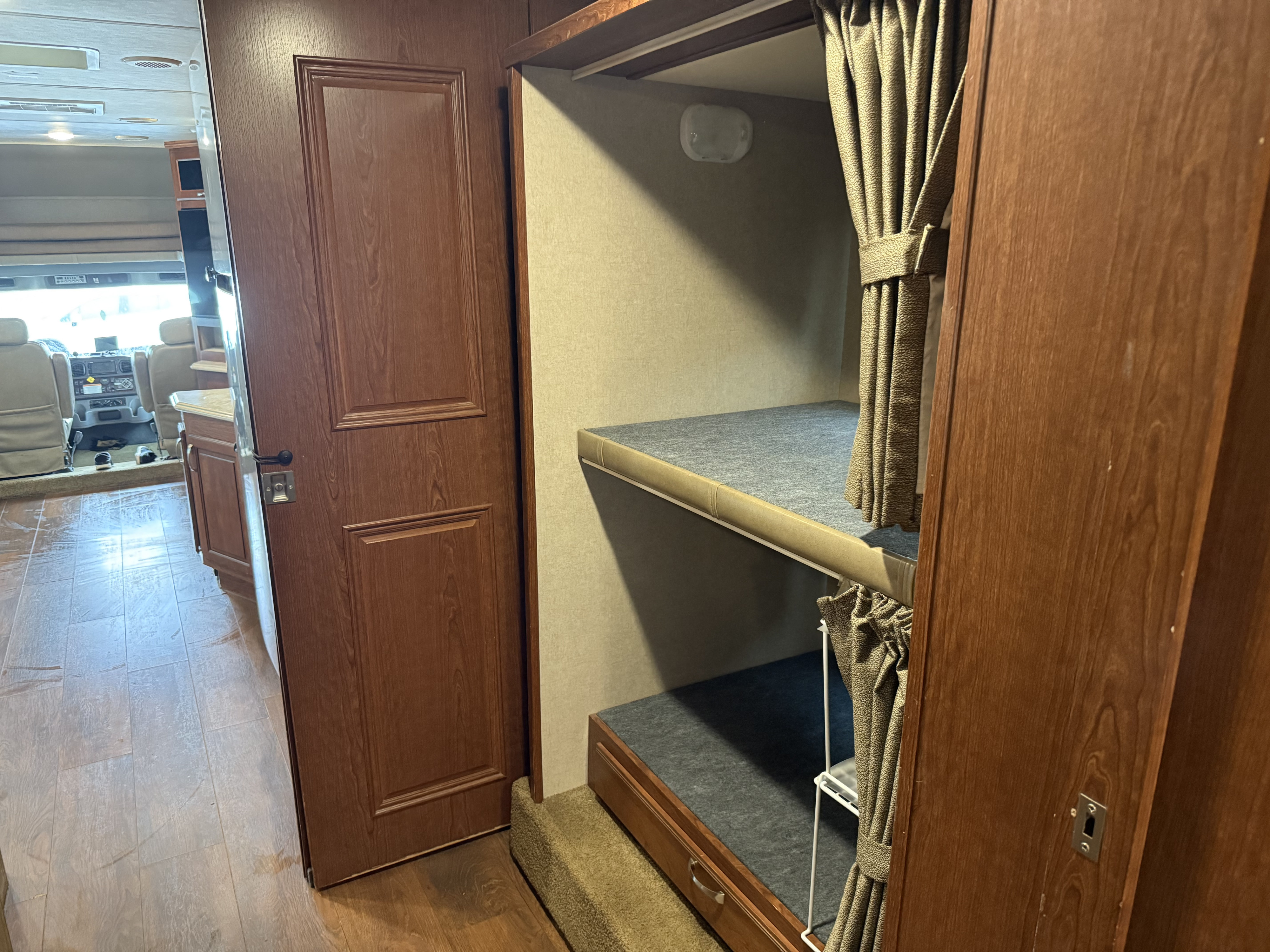 This RV rental's interior features cozy bunk beds with curtains on the right, providing a clear view to the front cockpit.. Force HD 2017