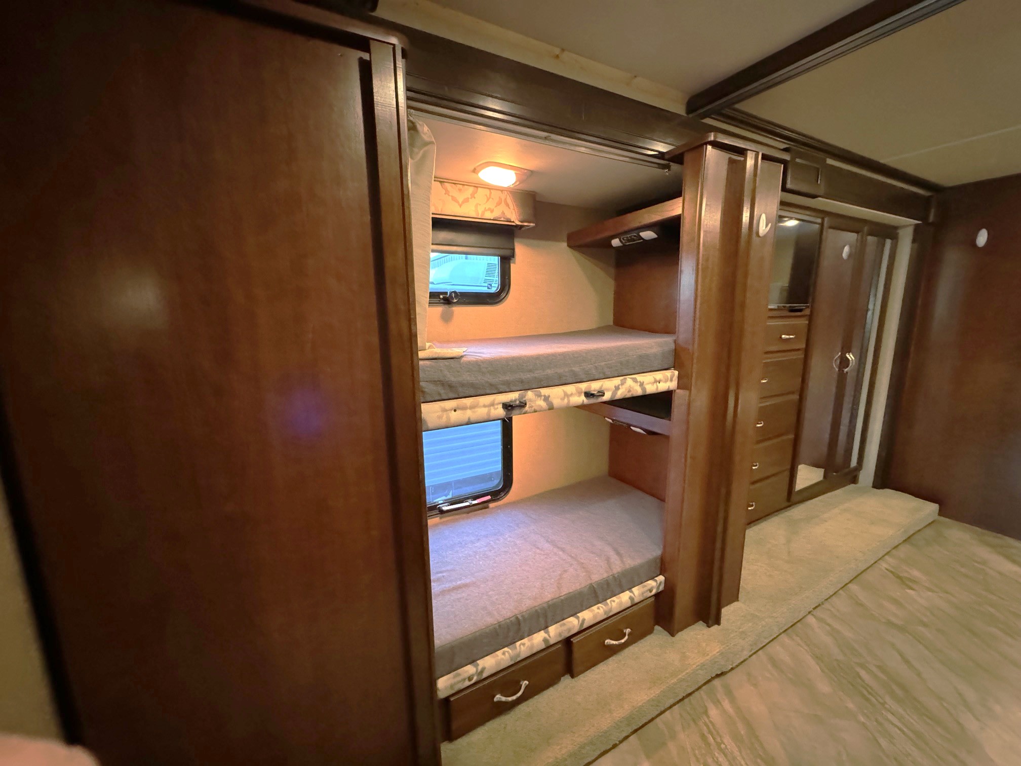 RV rental interior featuring comfortable bunk beds with windows and integrated storage drawers. Ideal for family trips.. Fleetwood Bounder 2017