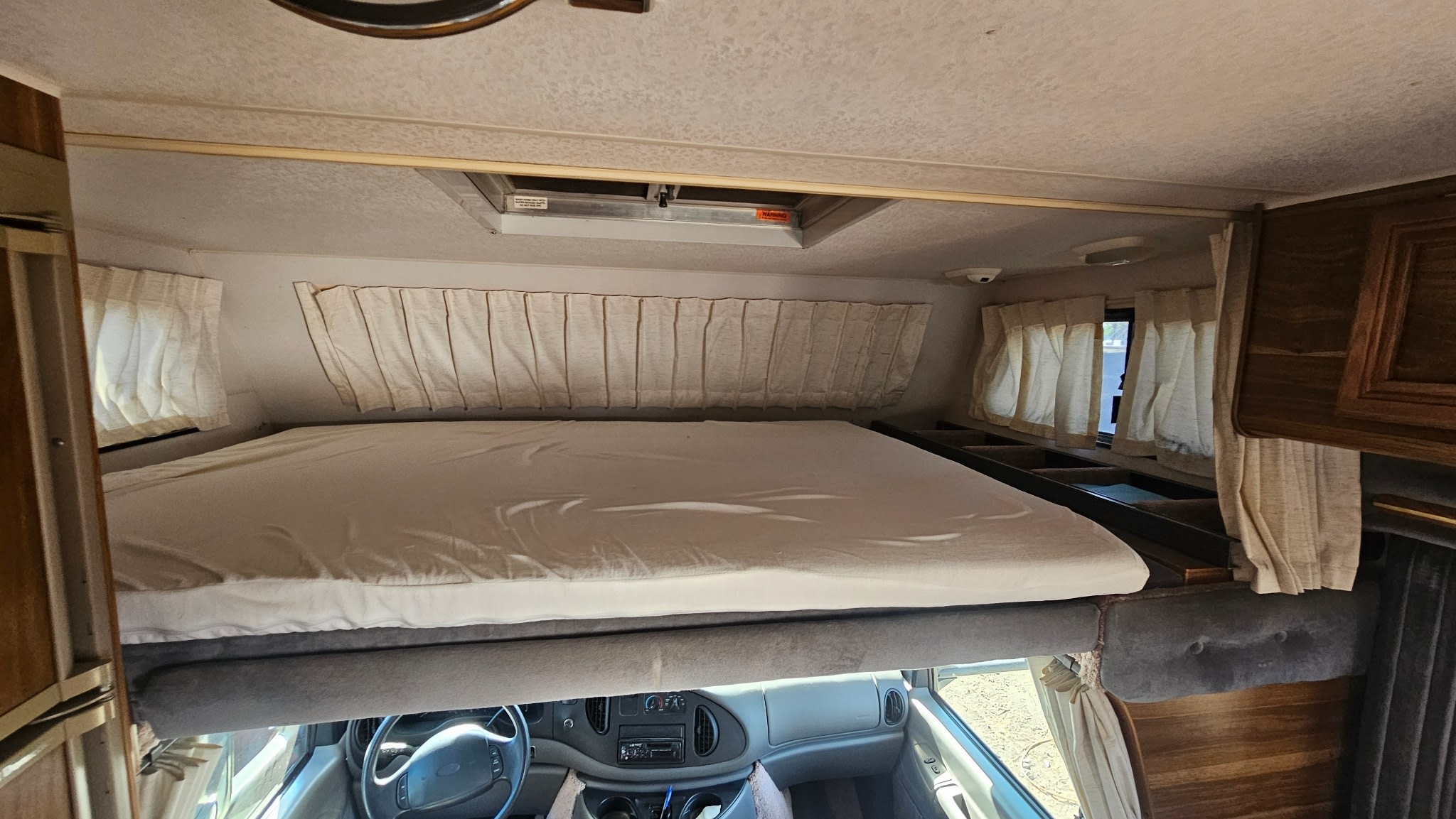 This rv rental features a spacious cab-over bunk bed, with the driver's area visible underneath.. Lazy Daze 26.5 1999