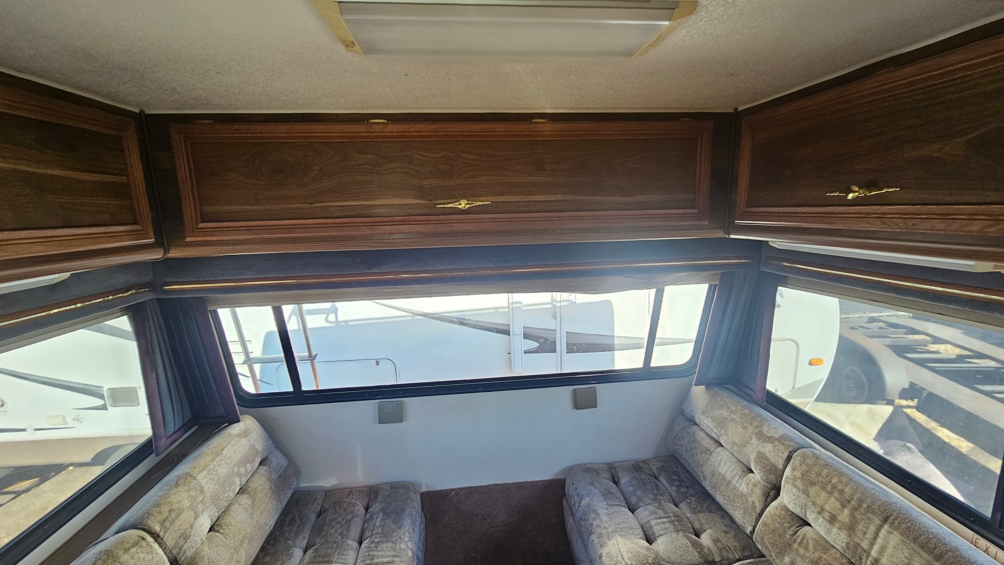 RV rental interior: cozy space with dark wood cabinets, large windows, and comfortable upholstered seating. Ready for adventure!. Lazy Daze 26.5 1999